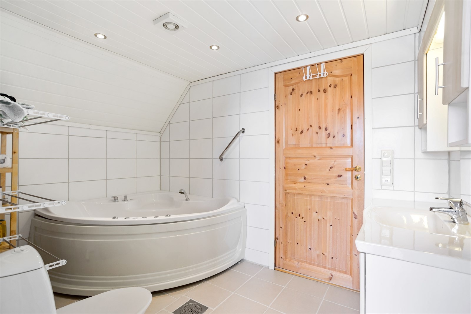 Helfliset og romslig baderom i nøstet, utstyrt med boble-hjørnekar, klosett og servant. Galleribilde