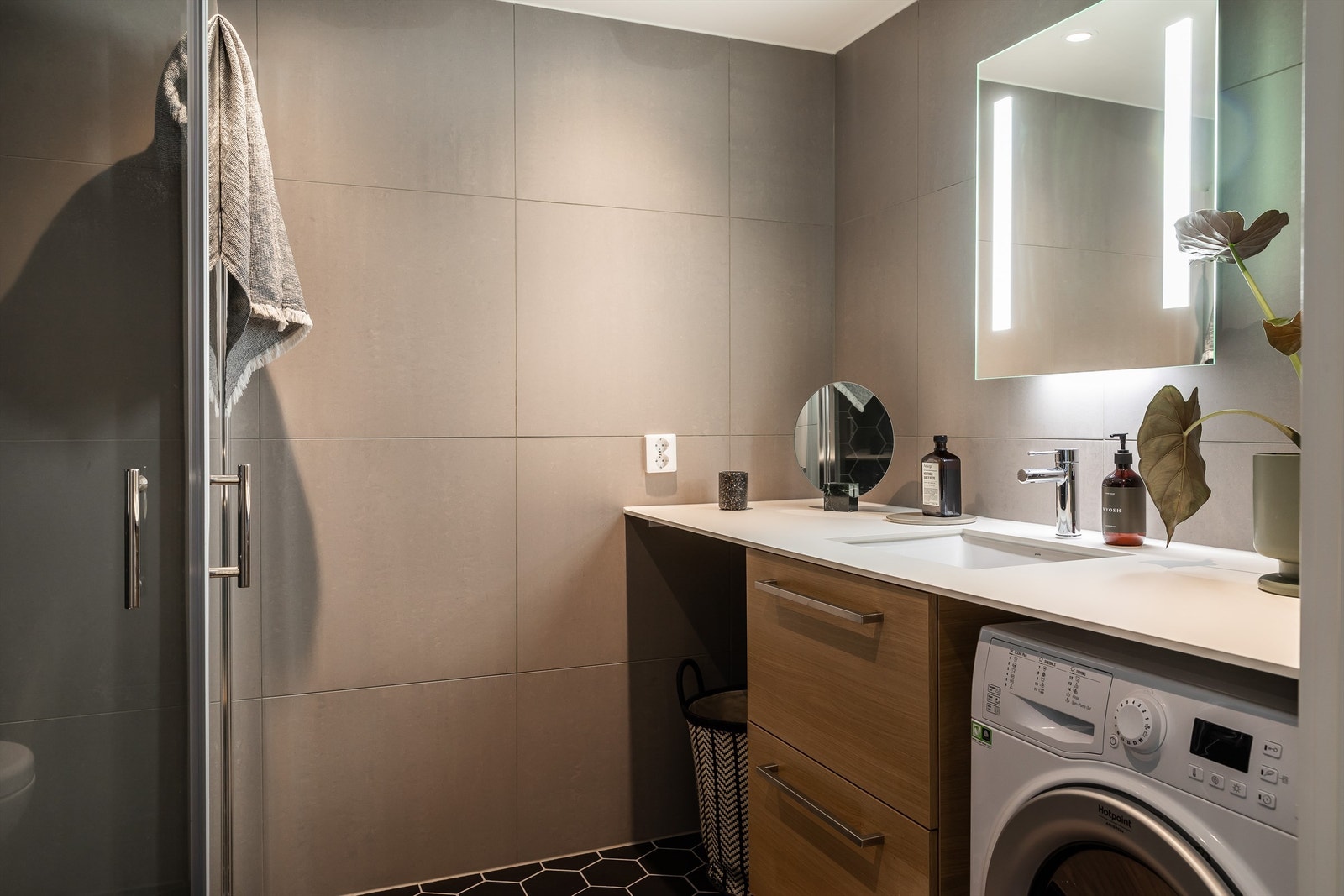 Innbydende bad på 5 m². innredet med baderomsmøbel med underskap, speil med integrert LED-lys, vegghengt WC med softclose og regnfallsdusj fra Grohe. Galleribilde