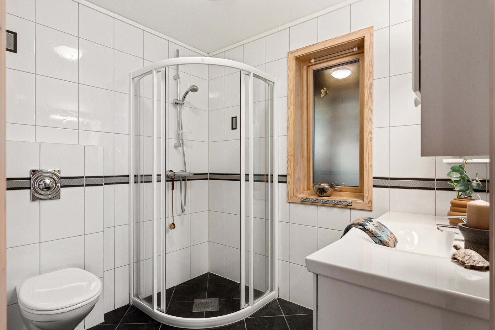 Det har frittstående toalett, dusjhjørne med buede skyvedører og servantinnredning Galleribilde