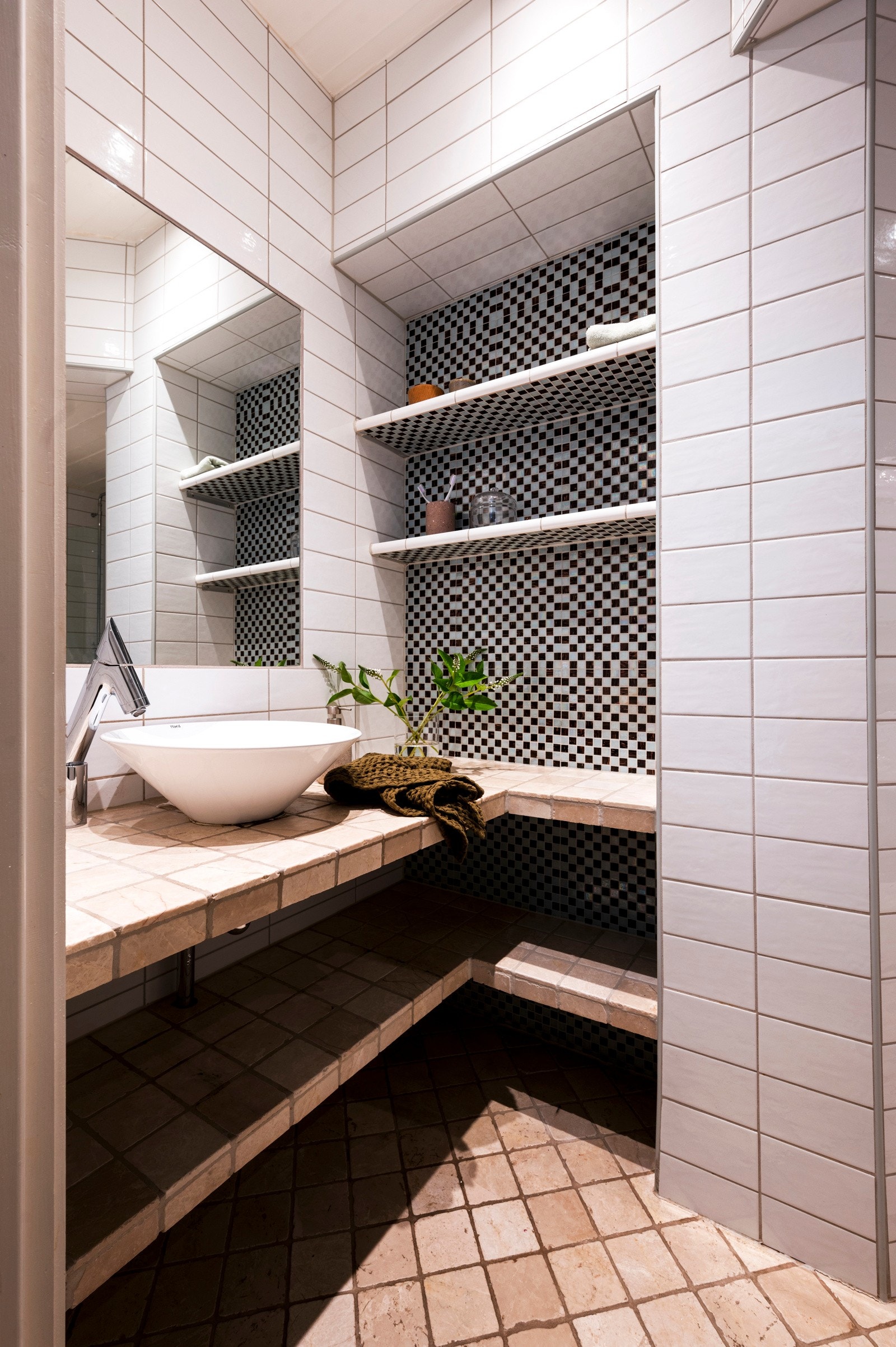 Baderomsinnredningen er plassbygd og flissatt, og består av en toppmontert servant på en benk, åpne hyller og innfliset speil. Galleribilde