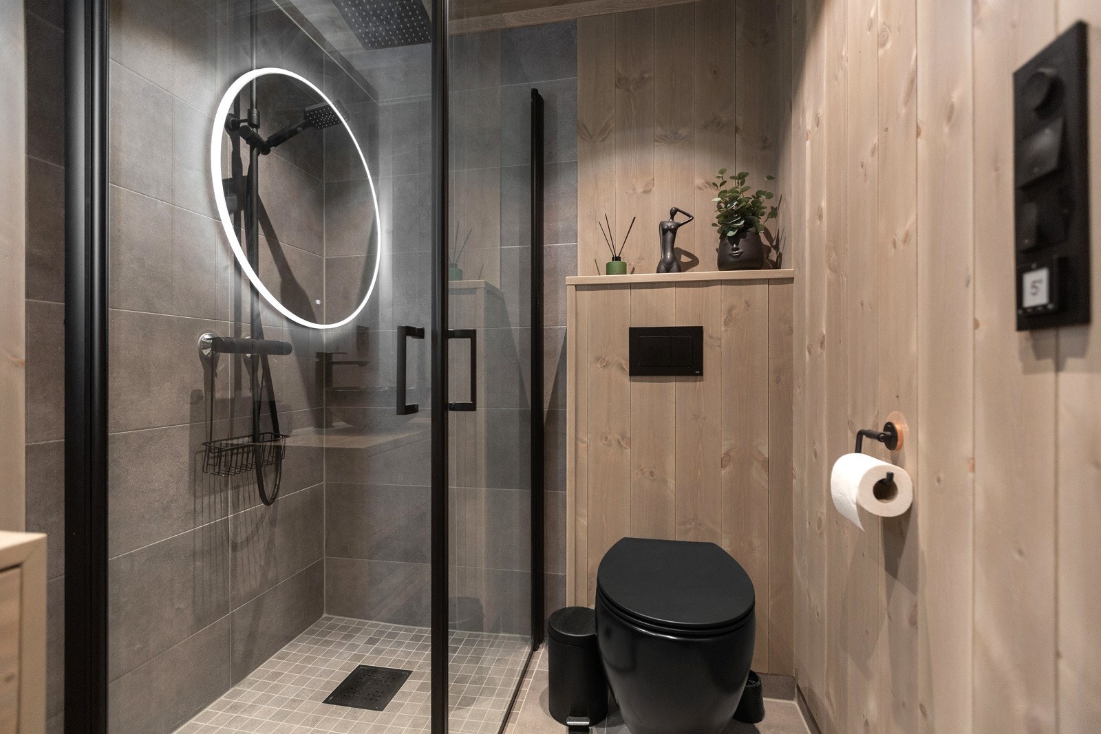 Badene er holdt i samme stil med flislagt gulv, downlights, panel på vegger og flislagte vegger i dusjsoner Galleribilde