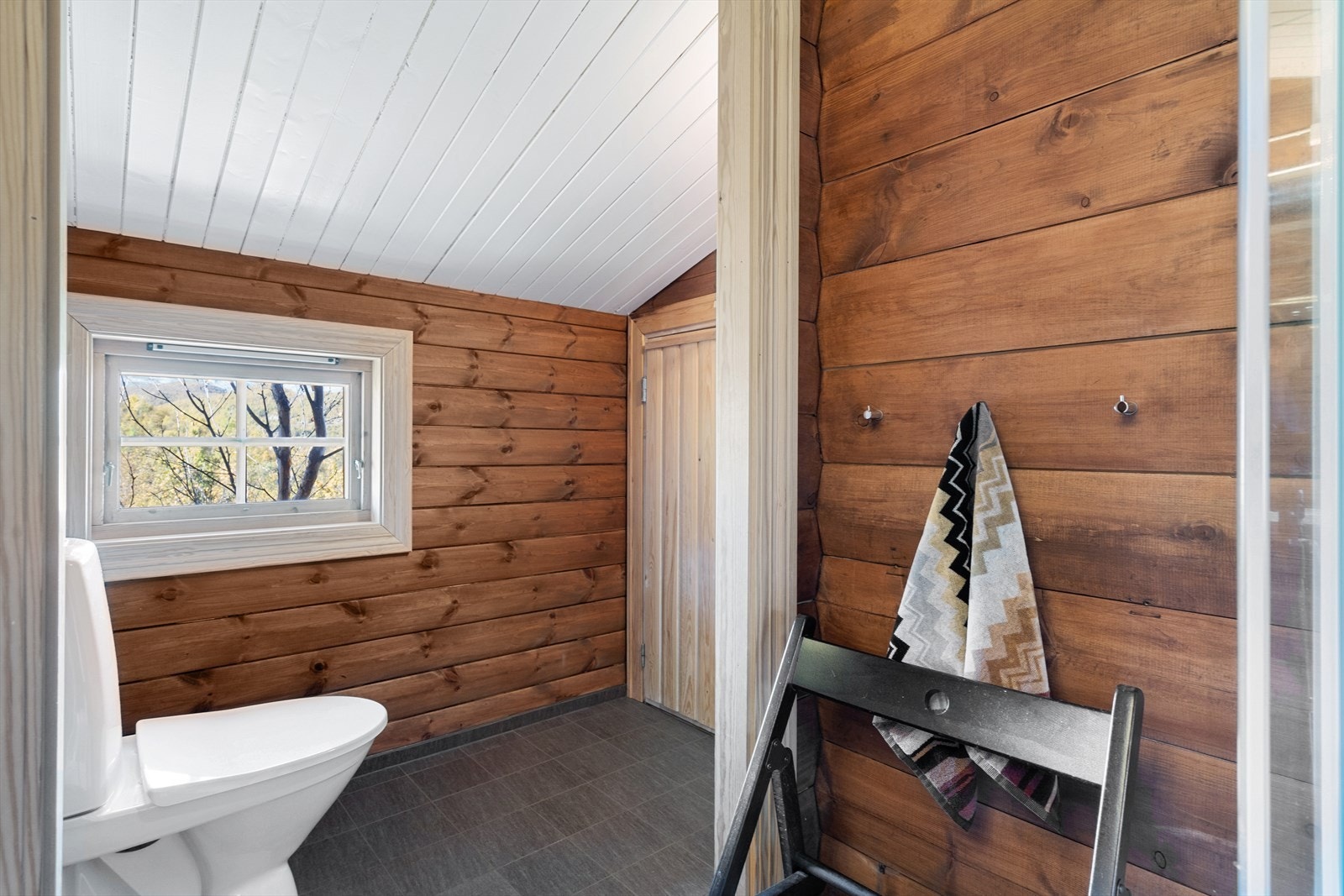 Bad har behandlede overflater som ellers i hytta, og flislagt gulv med varmekabler. Galleribilde