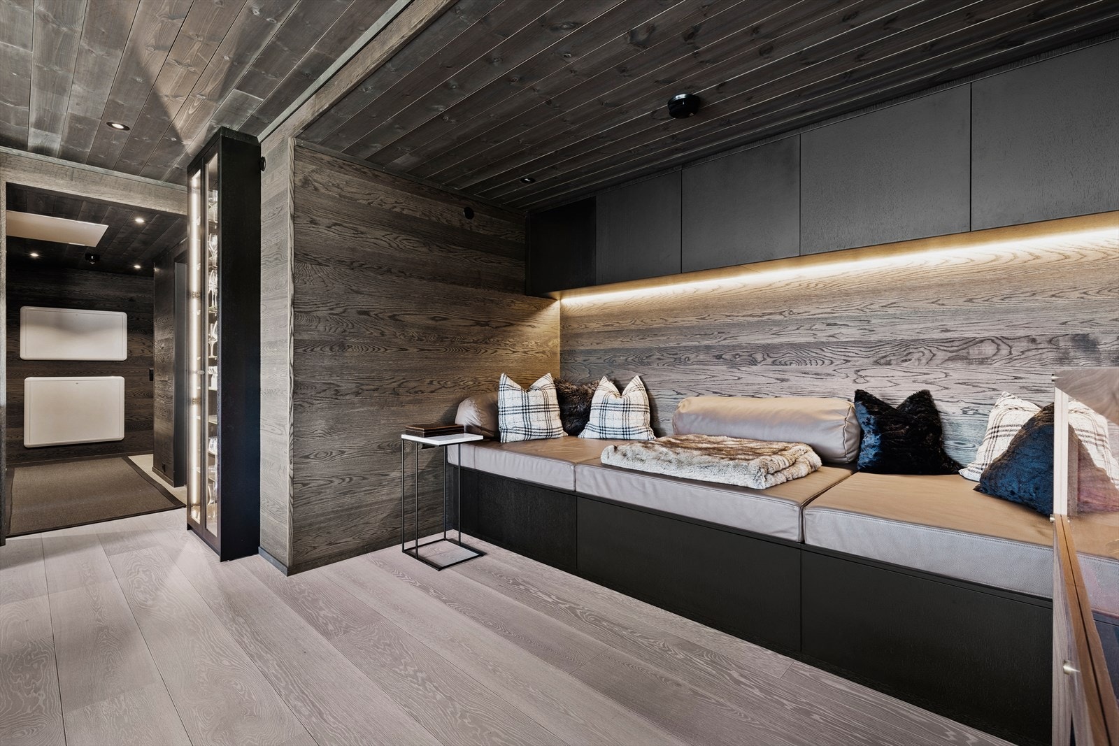 Ved den plassbygde sofaen med skreddersydde skinnputer er det ikke bare deilig å slappe av, men både over- og underskapene sørger for god og effektiv oppbevaring. Galleribilde