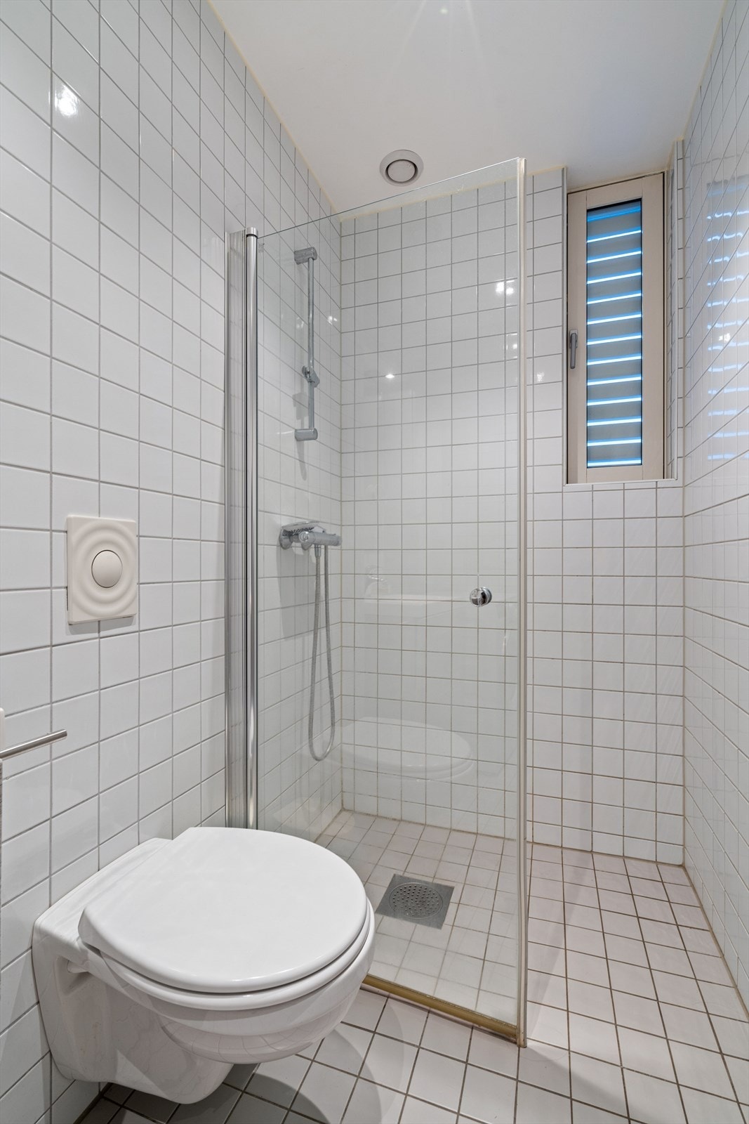 Badet er utstyrt med dusjhjørne med glasskillevegg og vegghengt toalett. Galleribilde