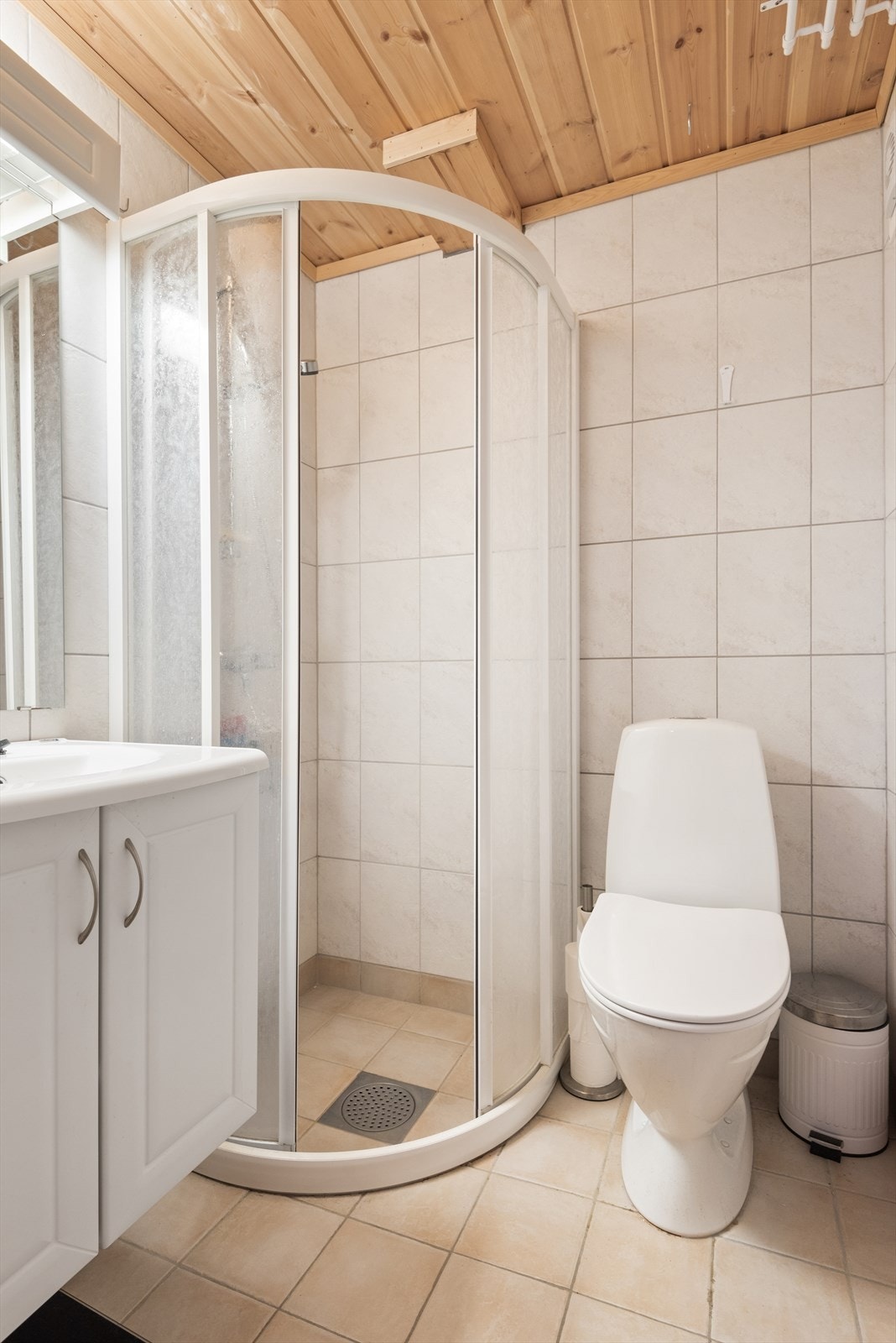 Flislagt bad i underetasjen med servantskap og dusjvegger Galleribilde