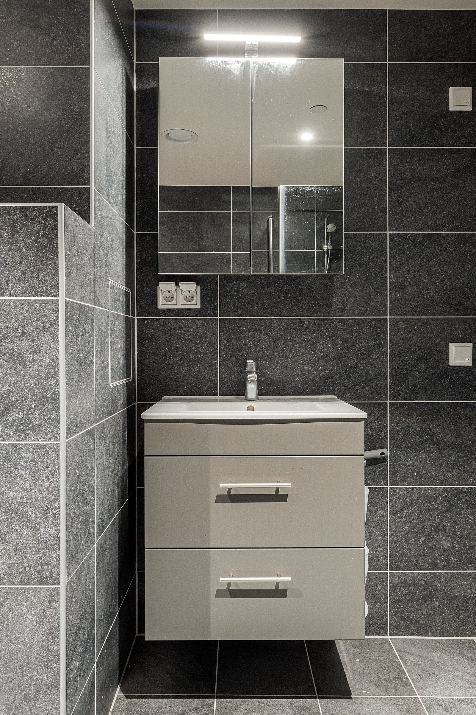 Badet er innredet med dusjhjørne, vegghengt toalett, baderomsinnredning med heldekkende servant. Galleribilde