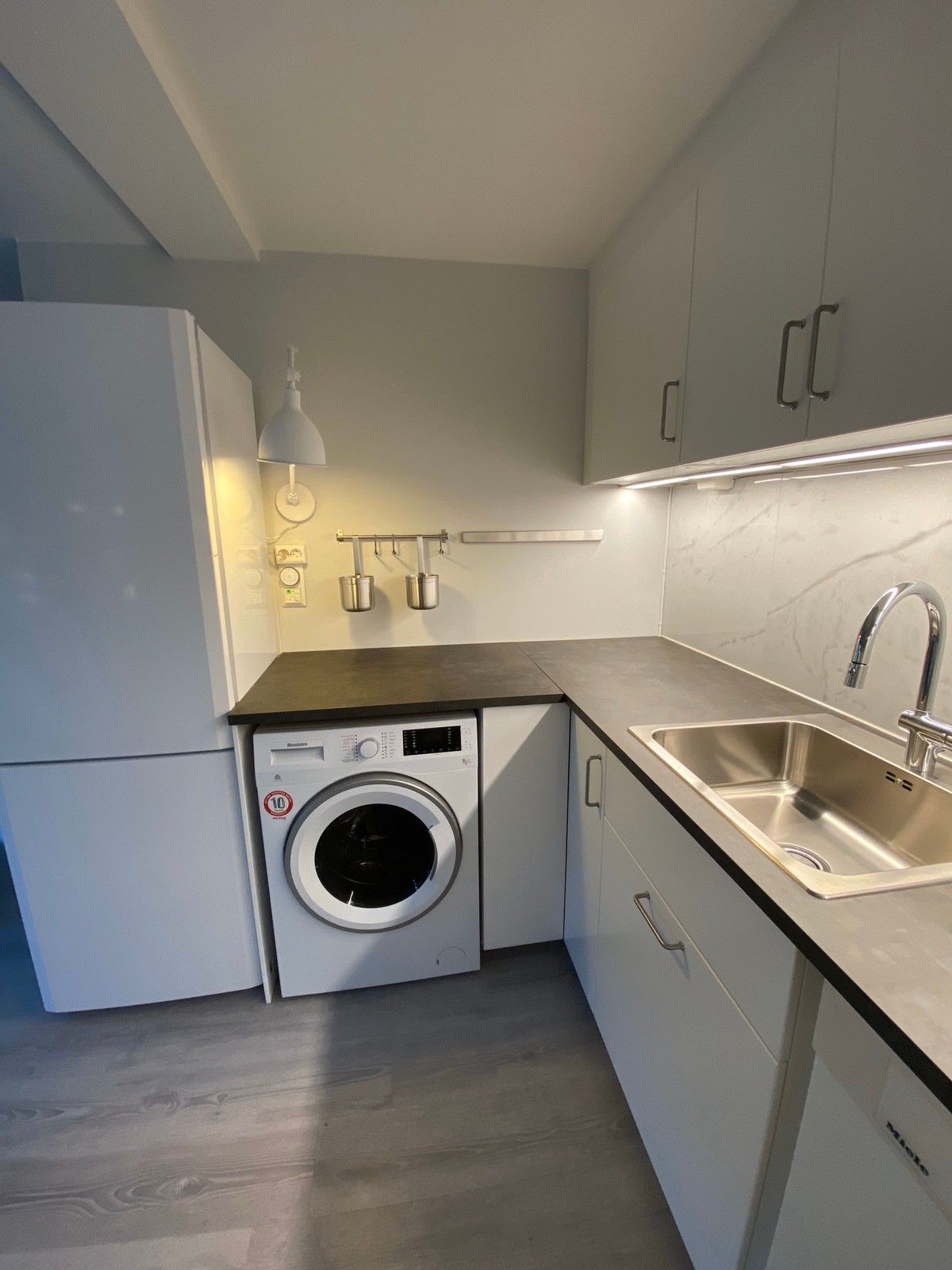 Kjøkken med kombi kjøl/frys-skap og kombi vaske/-tørkemaskin. Galleribilde