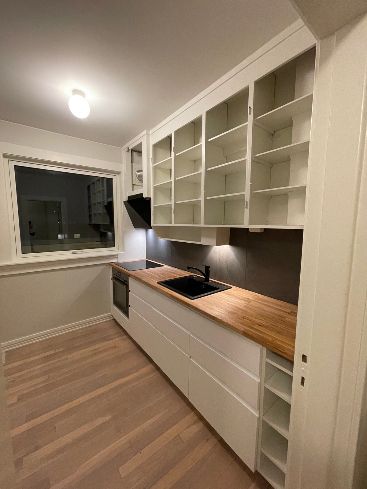 Kjøkken før montering av dører - godt med skapplass i plassbygde skap som går helt til taket. Galleribilde