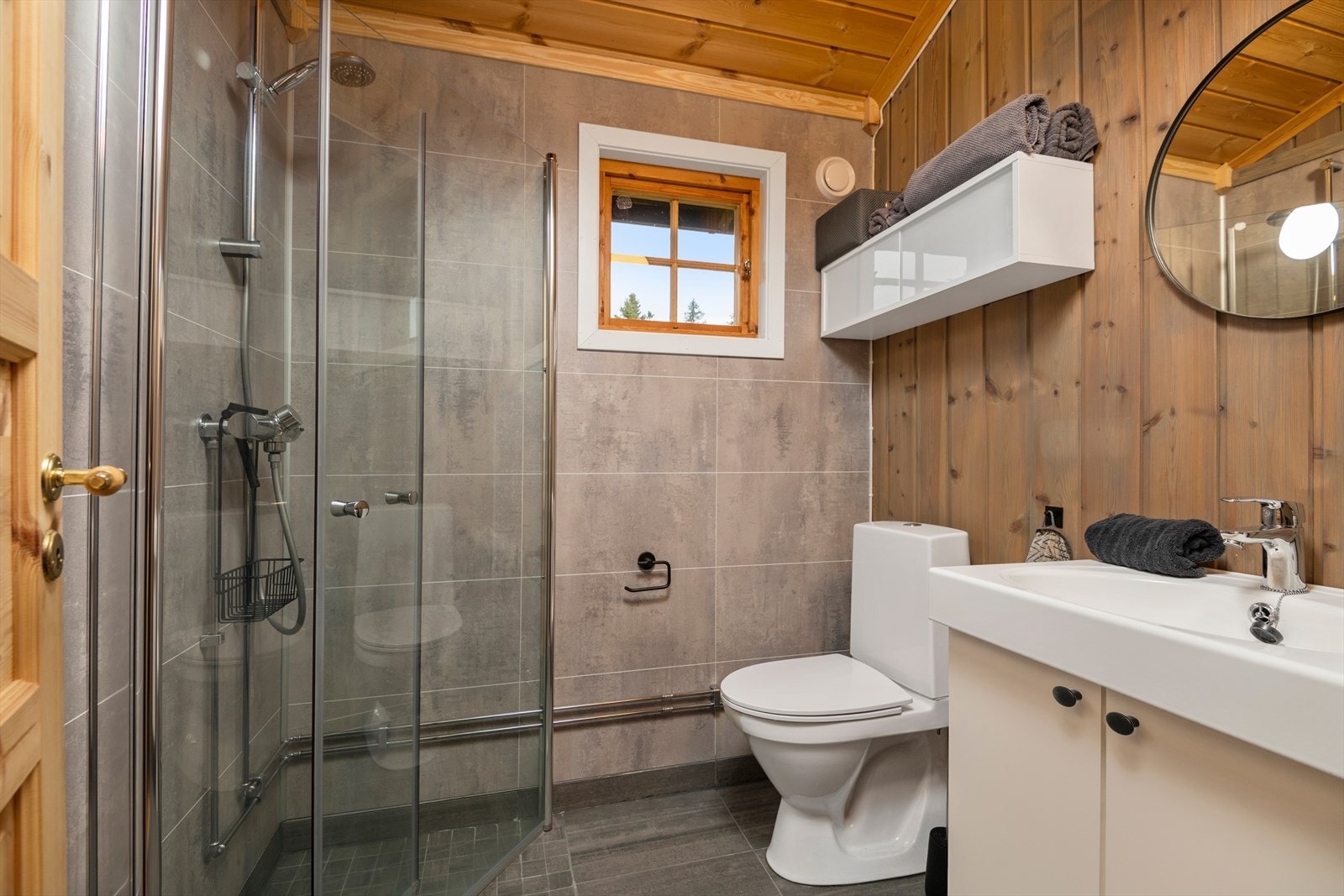 Nyoppusset bad/wc med flislagt dusjhjørne og gulv. Innfellbare glassdører i dusjen. Panelte vegger og himling. Galleribilde