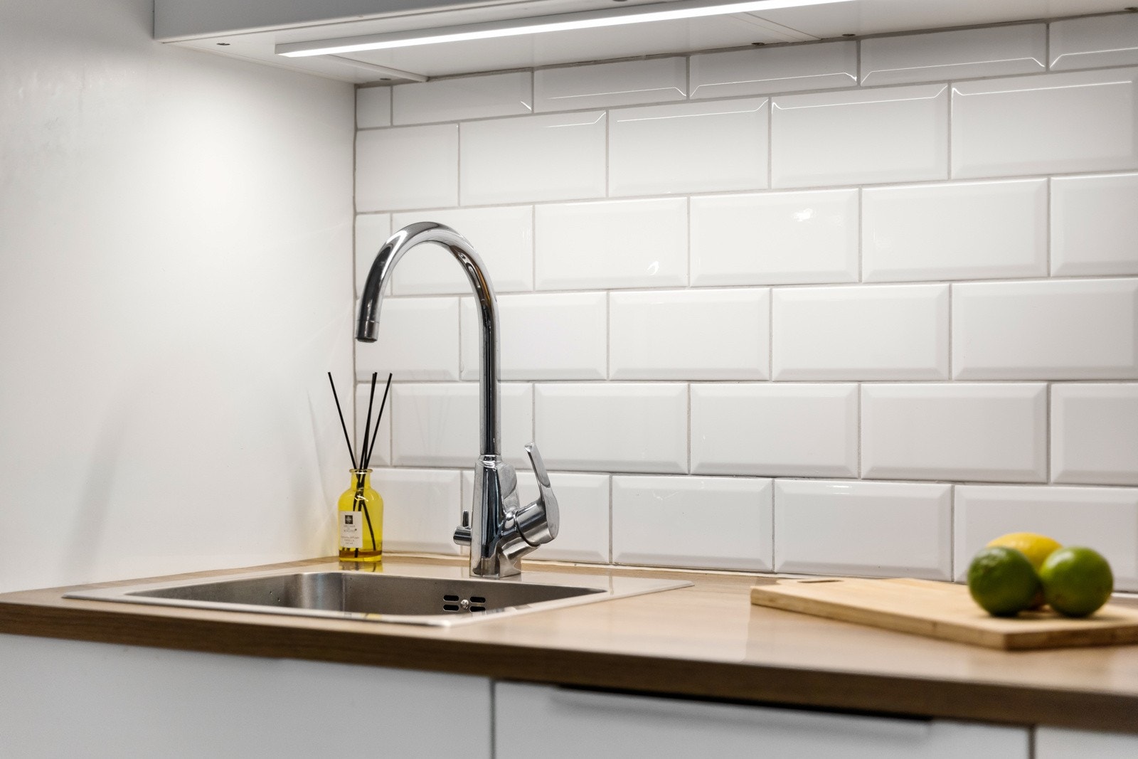 Kjøkkeninnredningen består av glatte, folierte fronter og laminat benkeplate med nedfelt kum i rustfritt stål. Ledlys under overskap gir gode arbeidsforhold. Galleribilde