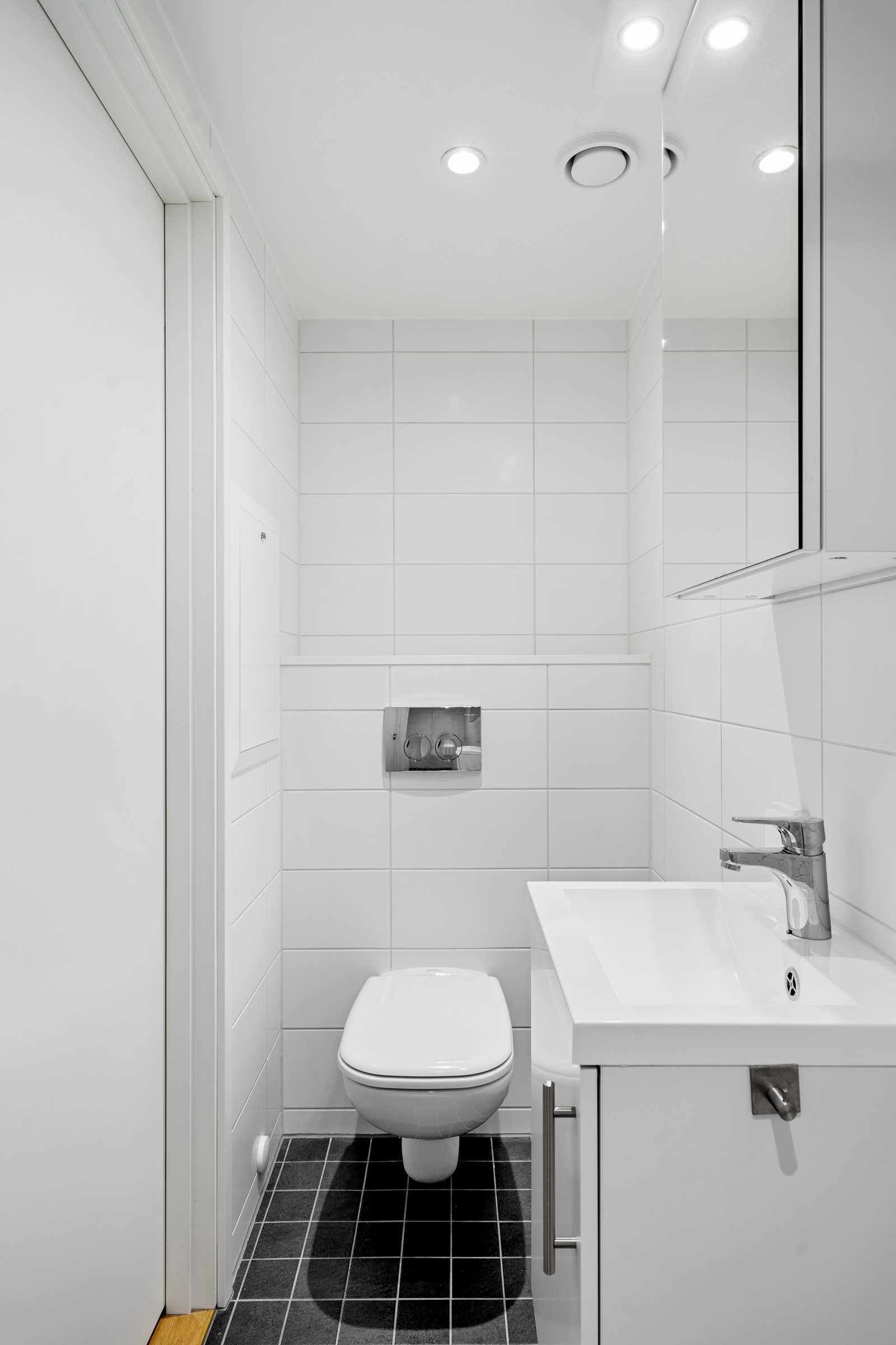 Hybeldelens bad består av toalett, servant og dusj - også her flislagte overflater.