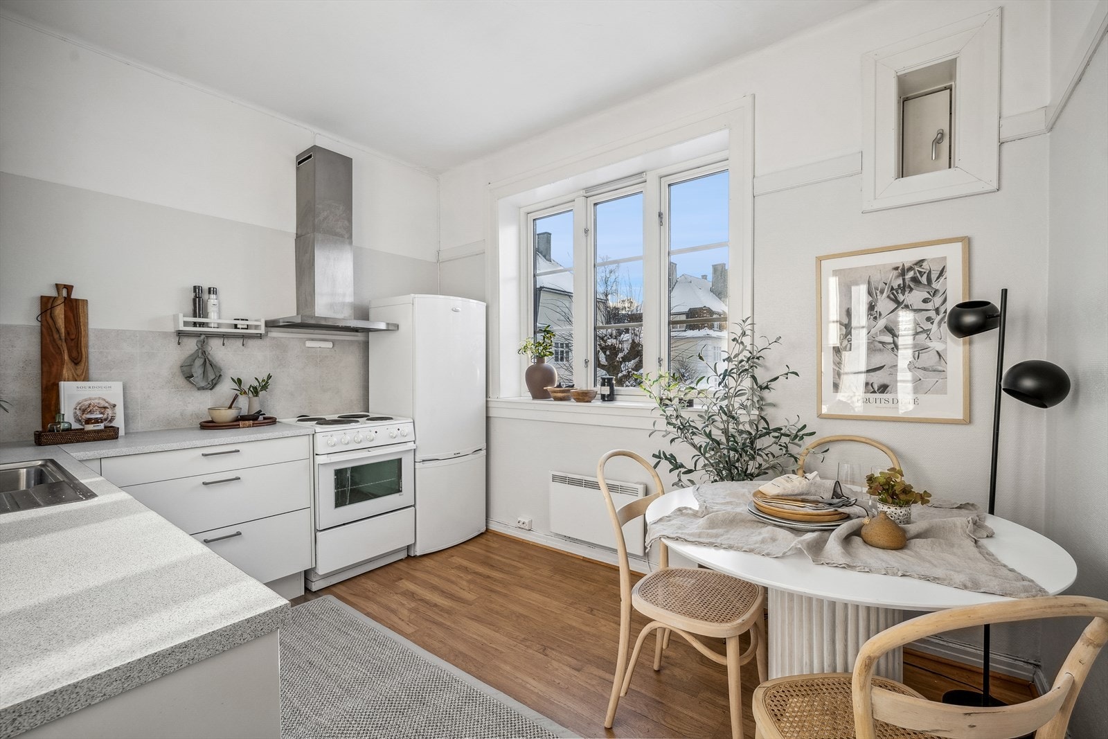 Kjøkkeninnredning med glatte fronter. Lyst og hyggelig rom med plass til en liten spisegruppe. Galleribilde