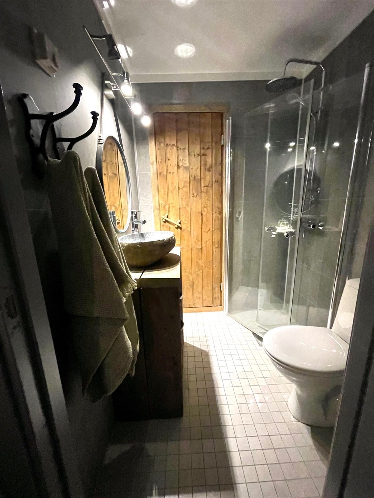 Et pent flislagt bad med dusjvegger, wc og innredning i samme stil som møblementet i stua. Adkomst til badstua Galleribilde