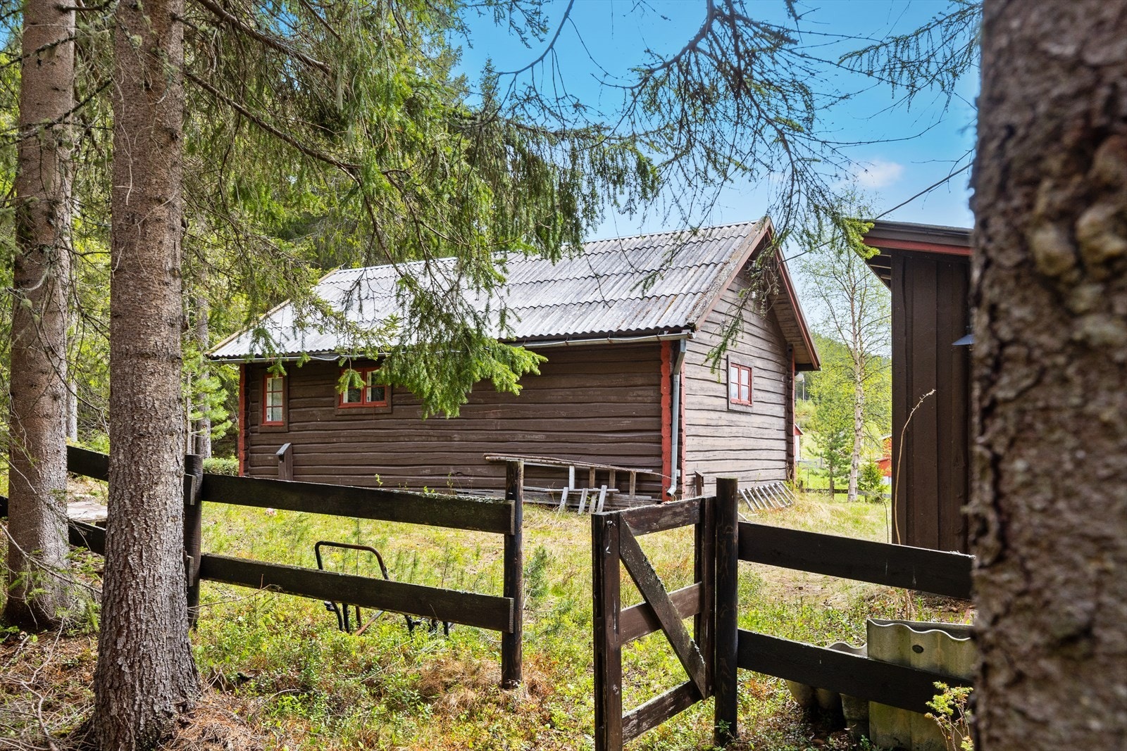 Delvis inngjerdet tomt rundt hytta med port inn til eiendommen. Galleribilde