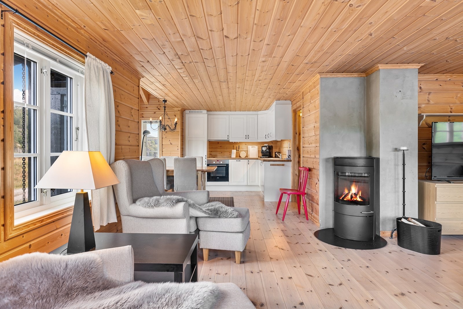 Romslig stue med vedovn. Furugulv og furu på vegger og tak Galleribilde