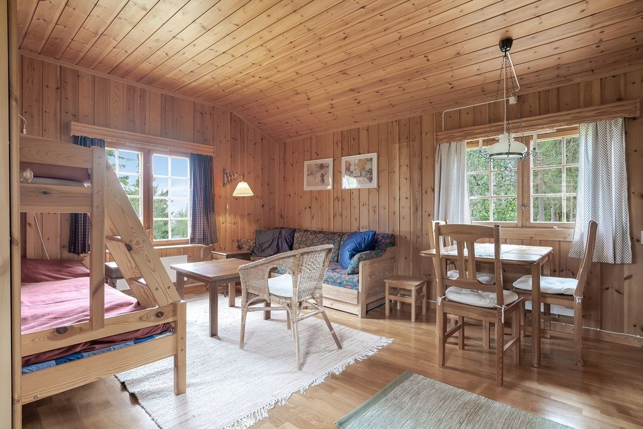 Stua i annekset er romslig med god takhøyde, ubehandlet trepanel på vegger og tak og eikeparkett på gulvet Galleribilde