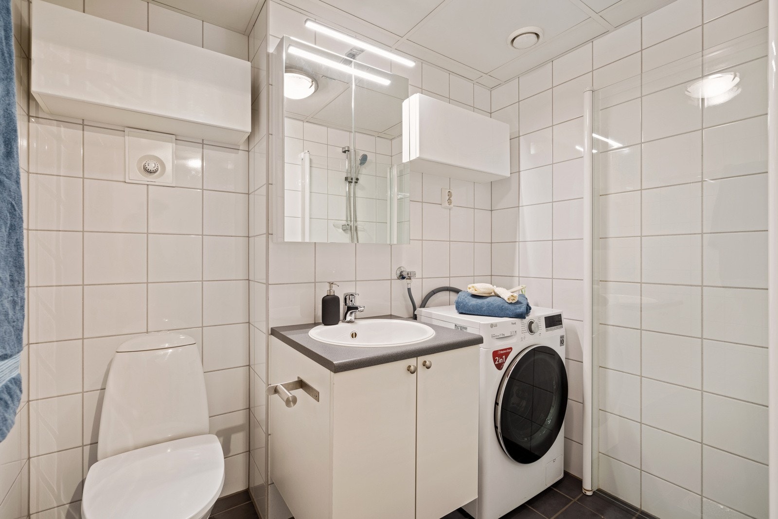 Lyst og delikat flislagt bad med ferdig opplegg for vaskemaskin Galleribilde