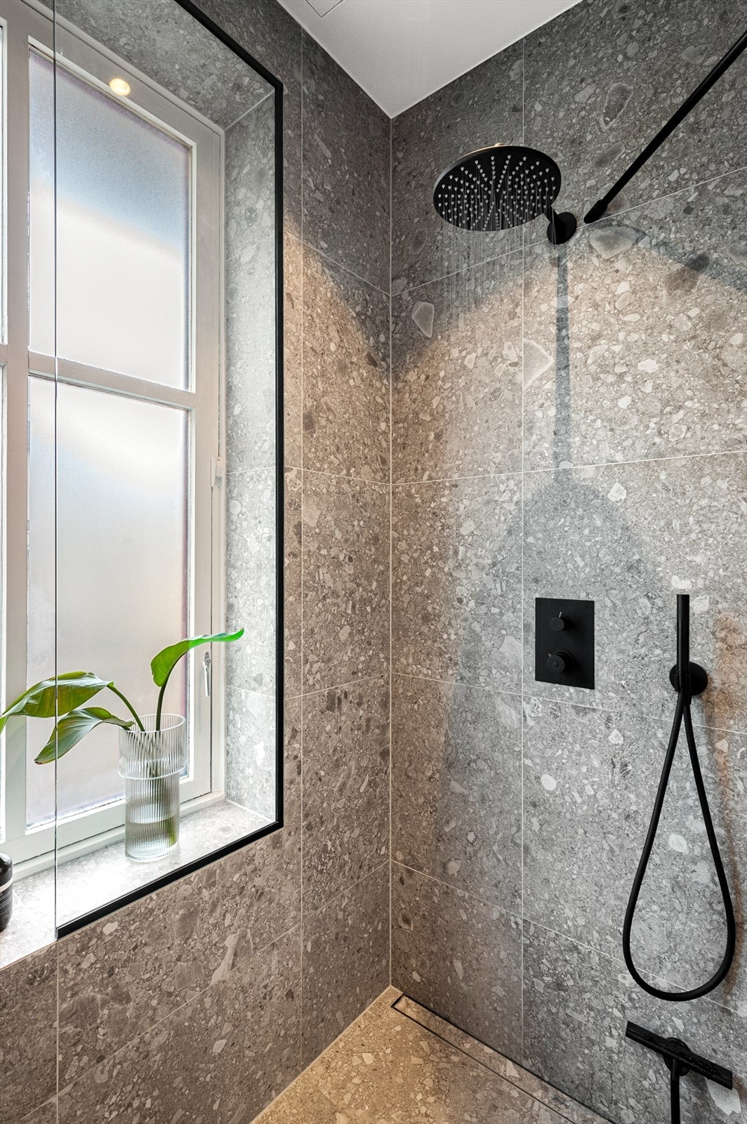 Dusjhjørne med regnfall, sort innebygget armatur fra Tapwell. Legg merke til det avlange sluket. Galleribilde