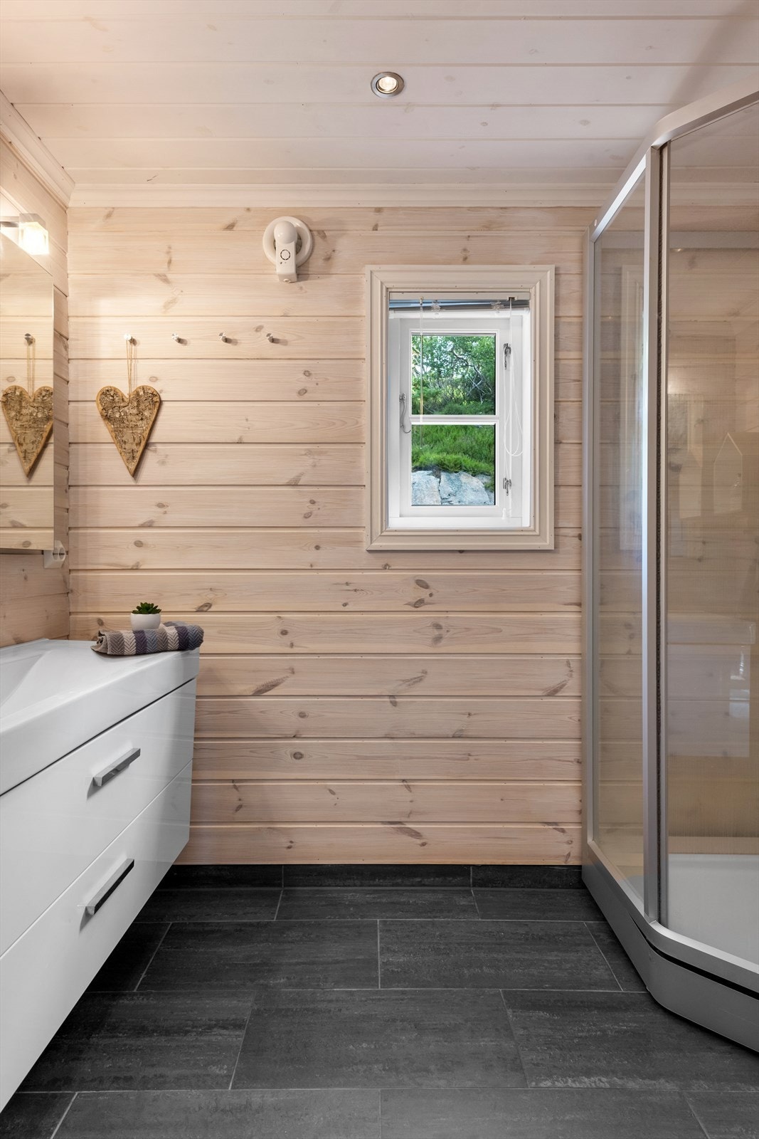 Praktisk og moderne bad med pene flis og varme i gulv. Fin kontrast mot lune panelvegger. Galleribilde