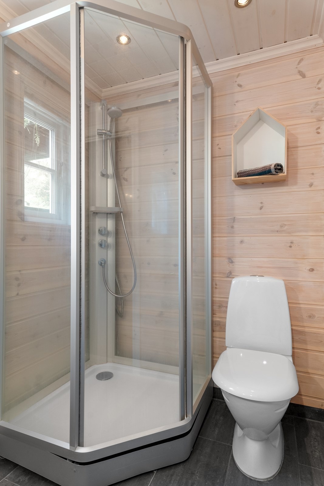 Praktisk og moderne bad med pene flis og varme i gulv. Fin kontrast mot lune panelvegger. Galleribilde