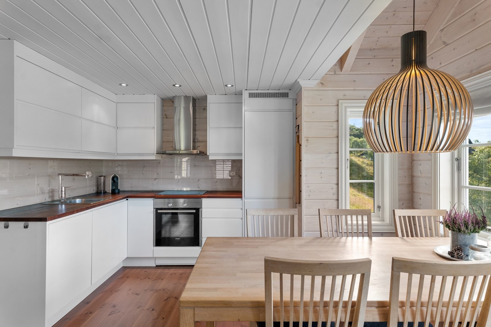 Åpen kjøkkenløsning trukket vekk fra hovedstuen, men i direkte kontakt med spisestuen. Koselig, sosialt og praktisk. Galleribilde