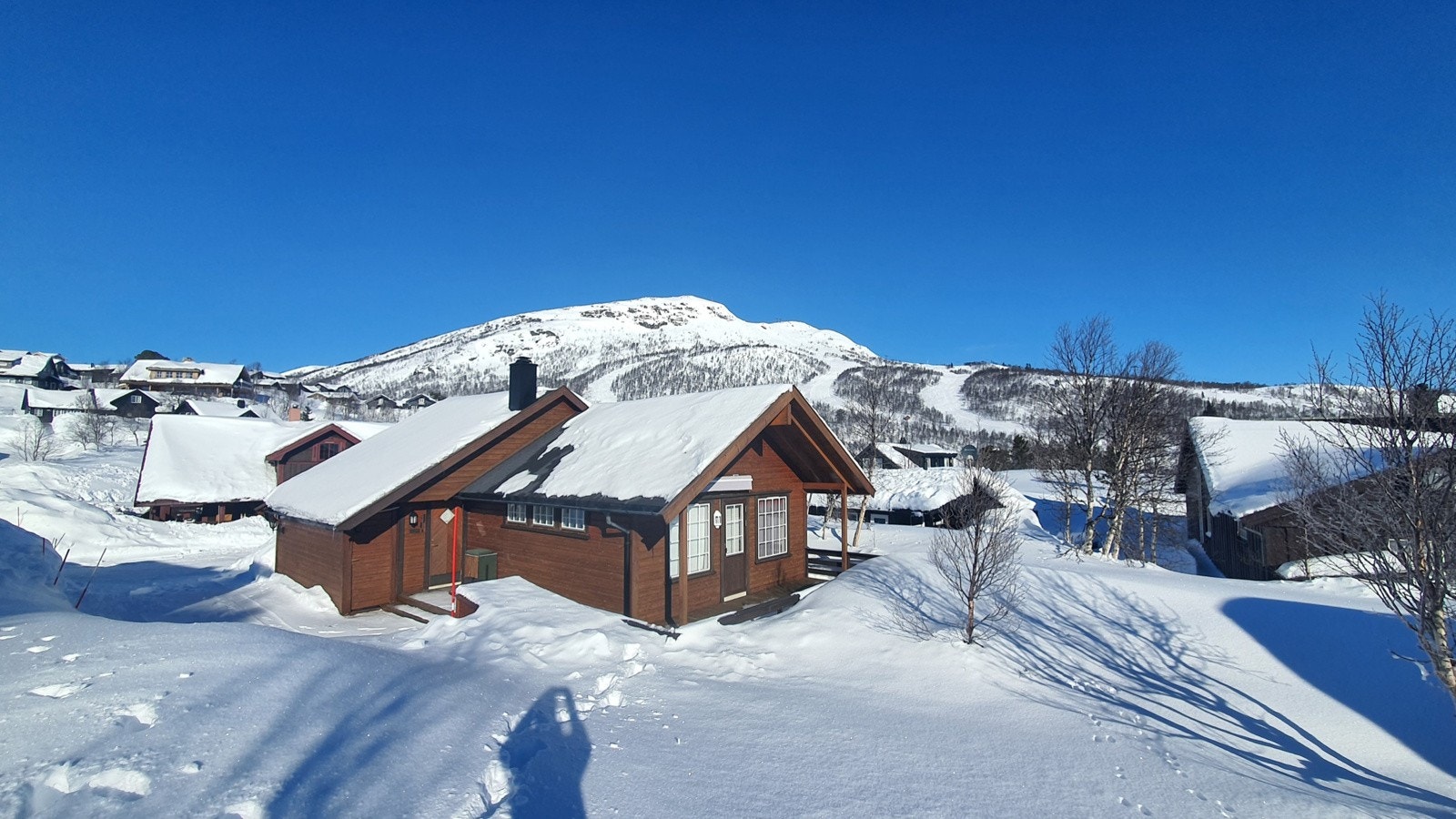 Hytten ligger høyt opp i fjellparken med alpinanlegget i bakgrunnen. Galleribilde