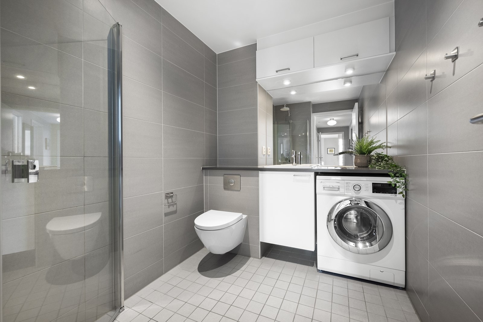 Delikat og romslig bad med flislagte overflater og opplegg for vaskemaskin. Galleribilde