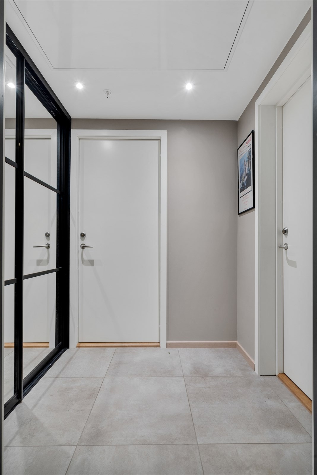 Felles gang med lekre fliser på gulv, downlights i himling og skyvedørsgarderobe med speildører Galleribilde