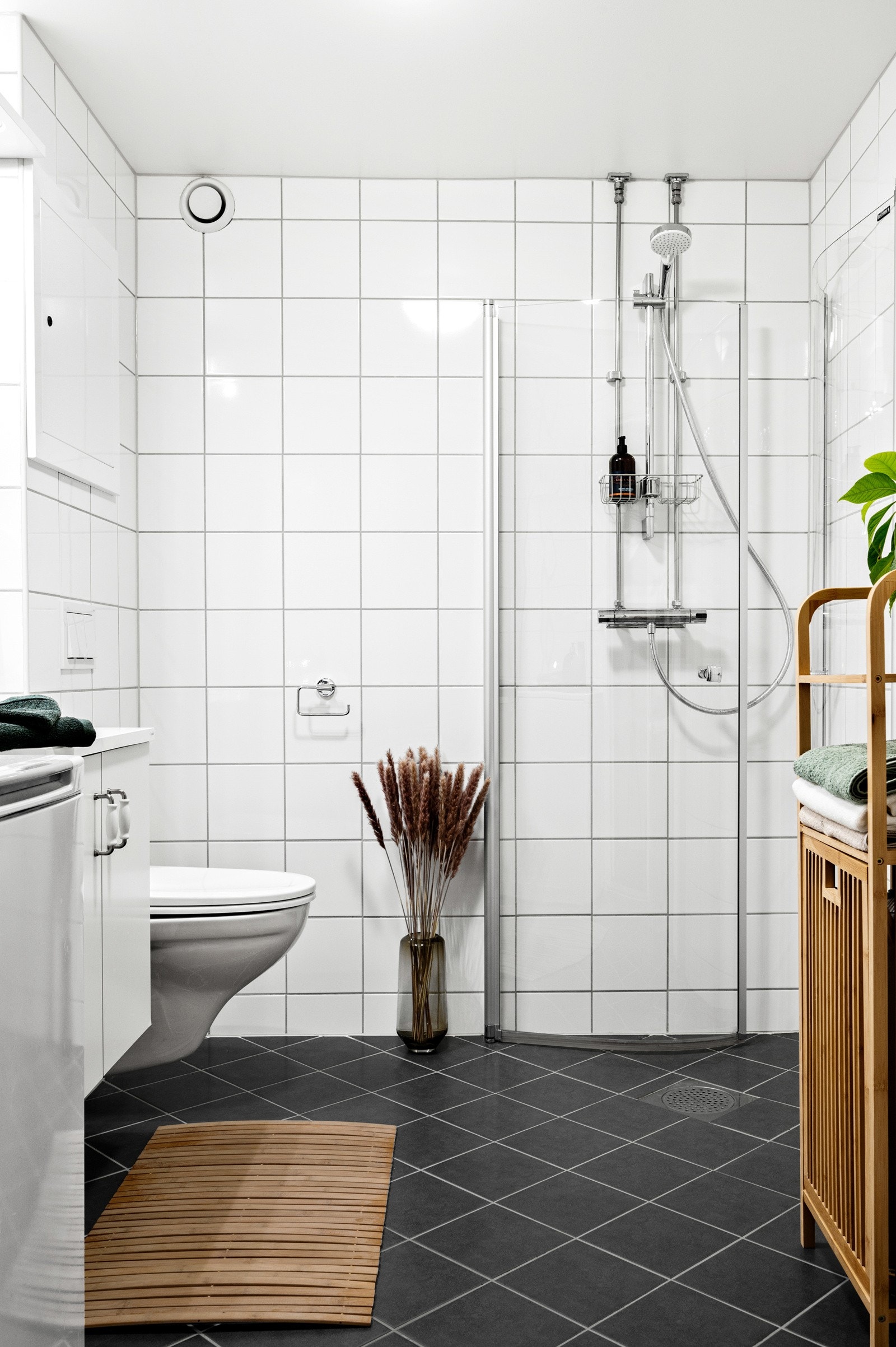 Badet er utstyrt med veggmontert toalett, dusjhjørne med dører i herdet glass, speilskap med overliggende spotlys, innredning med finerte fronter og heldekket servant. Galleribilde