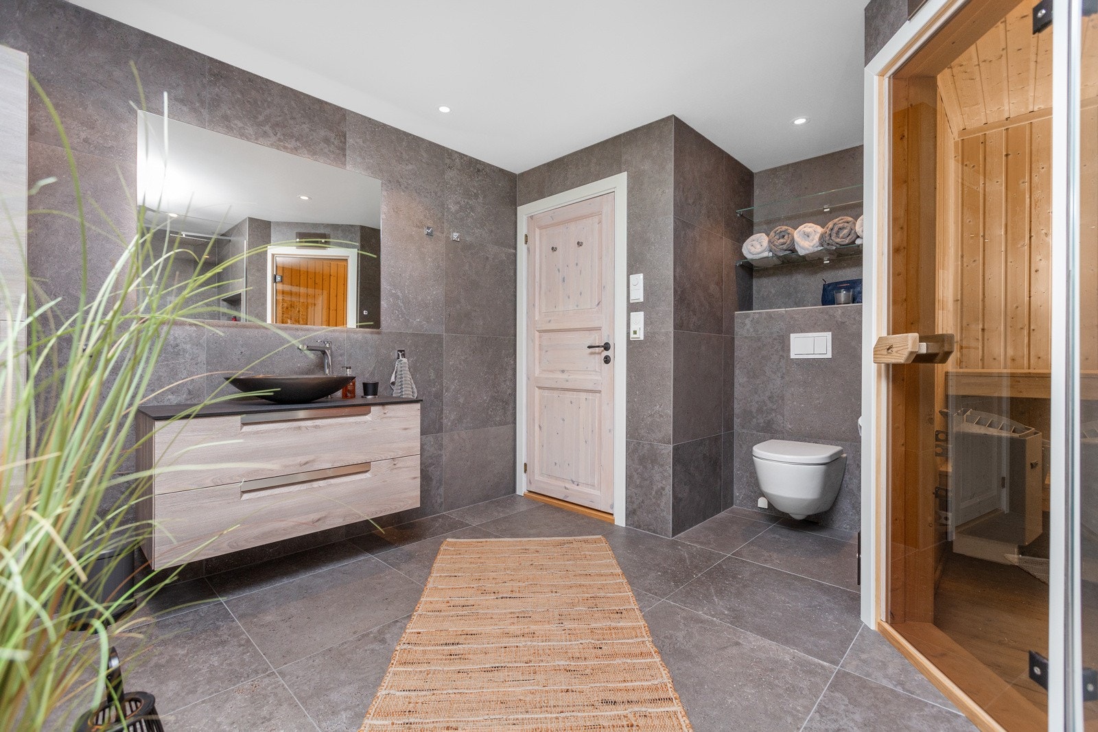 Moderne innredning med stilig rund håndvask, vegghengt toalett, dusjnisje samt inngang til badstue Galleribilde