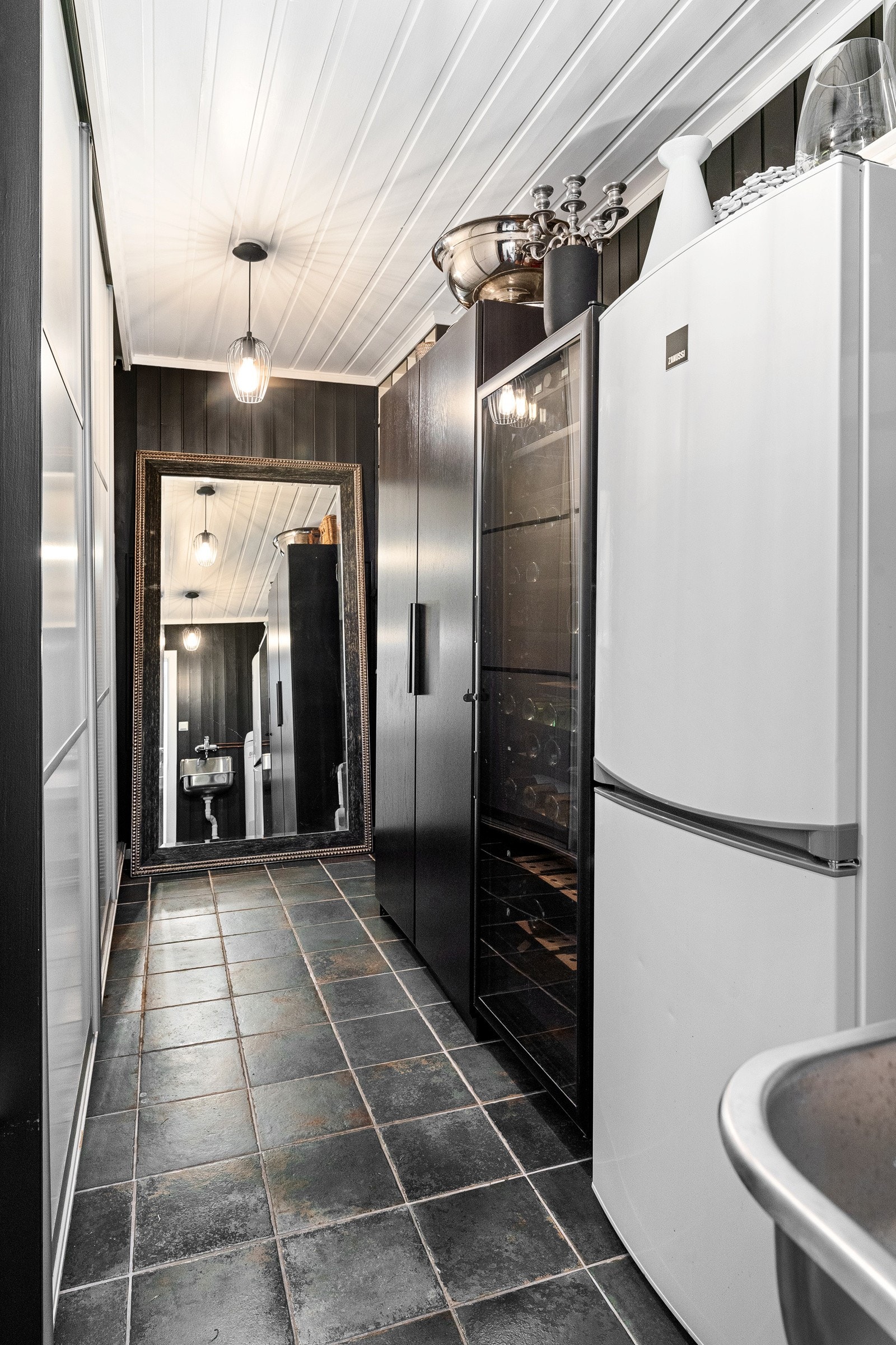 Praktisk garderoberom innredet med skyvedørsgarderobe, skap og vinskap. Galleribilde