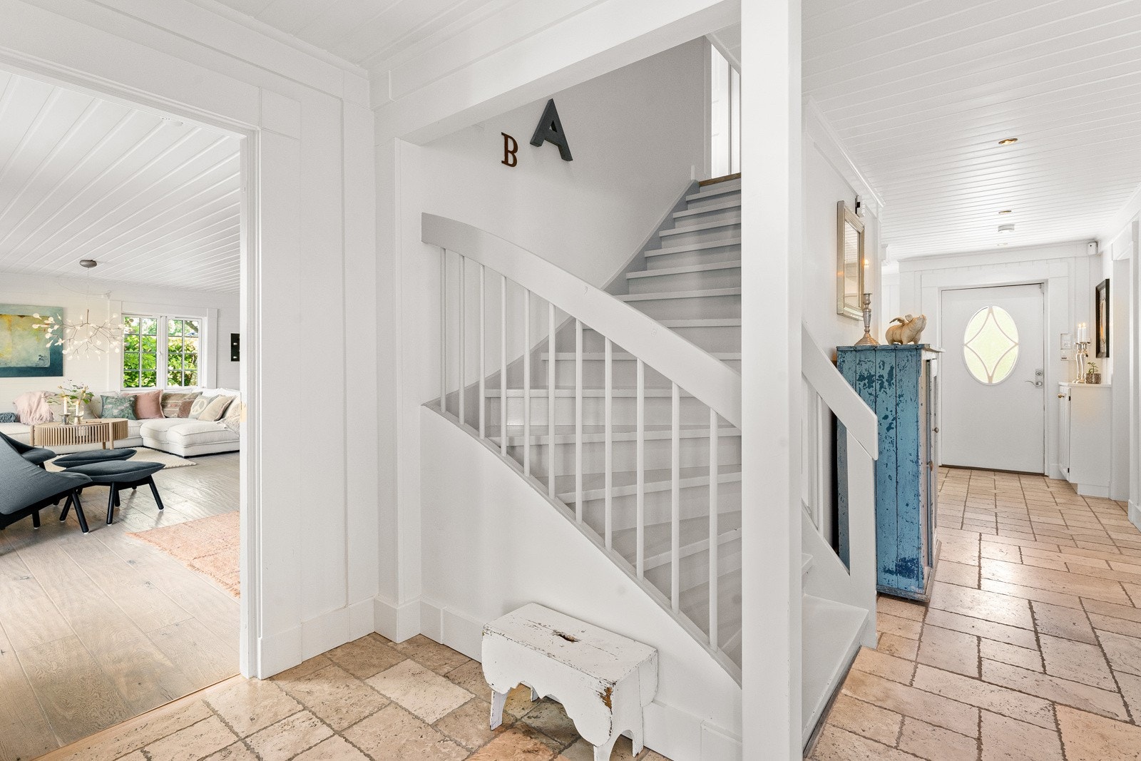 Entré/gang med downlights i hvitmalt himling, hvitmalt panel på veggene og beige marmorfliser over lun gulvvarme. Galleribilde