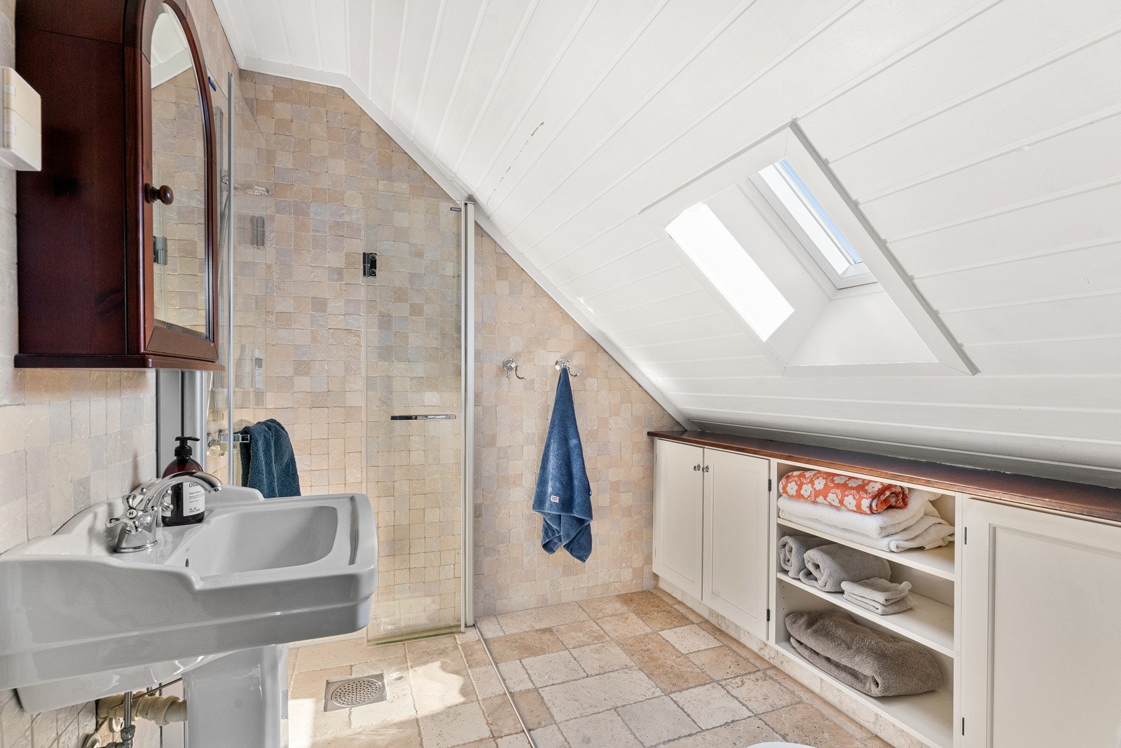 Flisene er av marmor og holdt i en rustikk stil. Videre er det gulvmontert toalett, gulvvarme og nyere takvindu i skråhimling. Langs kneveggen under skråhimlingen er det en hendig skapinnredning. Galleribilde