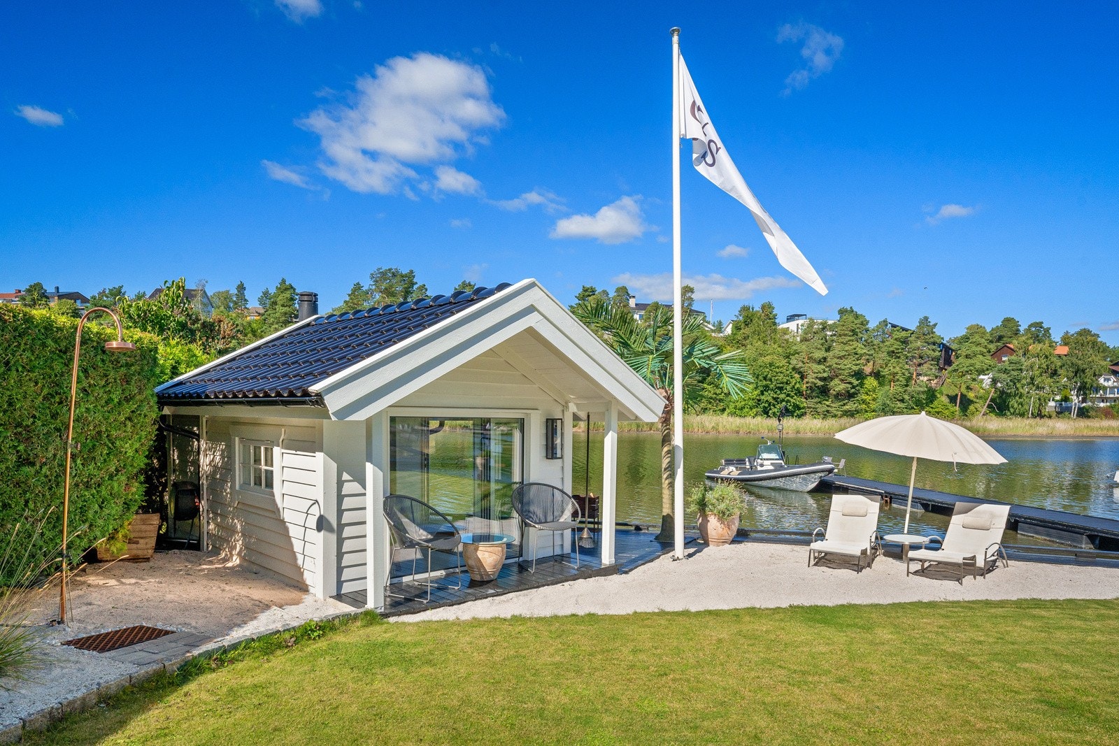 Hagen er innrammet av hekker, og nede ved vannet er det en sjøbod på ca. 12 omgitt av lys sand. Galleribilde