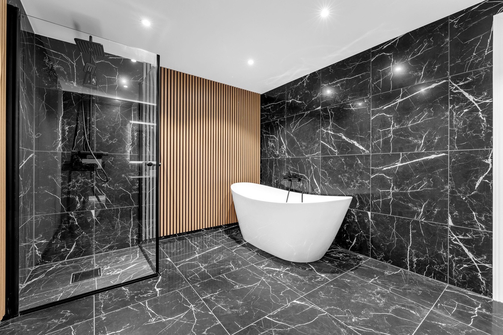 Stort frittstående badekar med dusj og dusjhørne med dører i glass. Galleribilde