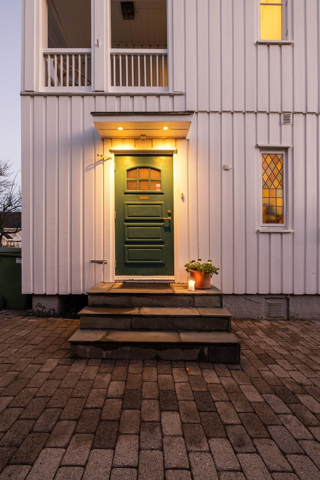 Inngangsparti med lite overbygg og skiferkledd betongtrapp fra 1963. Inngangspartiet ligger i tilknytning til eiendommens innkjørsel. Galleribilde