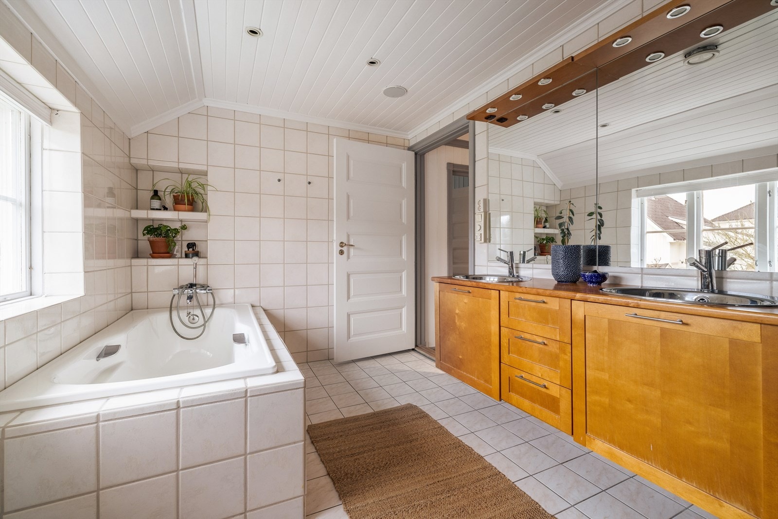 Romslig innredning med format fronter og heldekkende benkeplate av furu, med to nedfelte stålvasker. Speil og overlys med el-stikk. Galleribilde