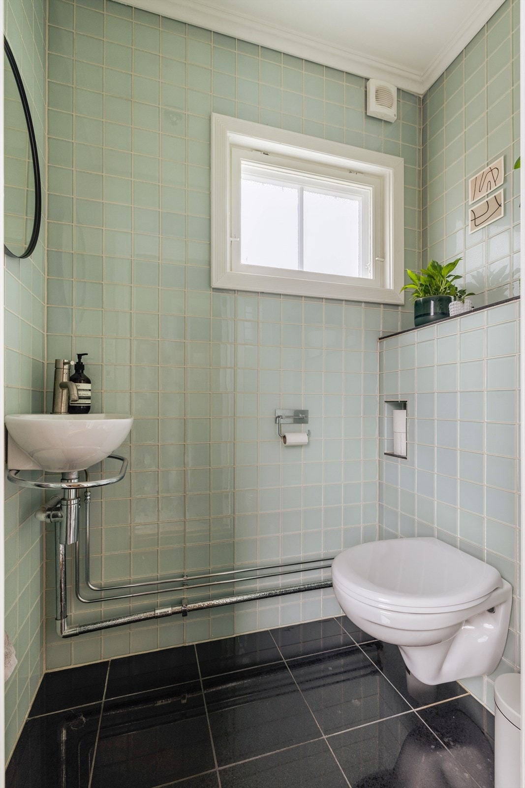 Toalettrom i 1. etasje er utstyrt med gulvvarme, håndvask og speil, samt vegghengt toalett. Flis på gulv og glassflis på vegger. Galleribilde