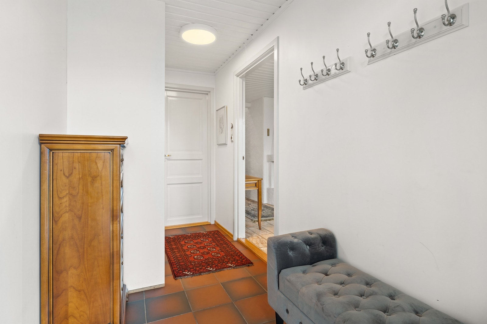Inn fra det overbygde inngangspartiet blir du møtt av en romslig entré med fliser og varme i gulv. God plass til oppheng av ytterjakker i skyvedørsgarderobe Galleribilde