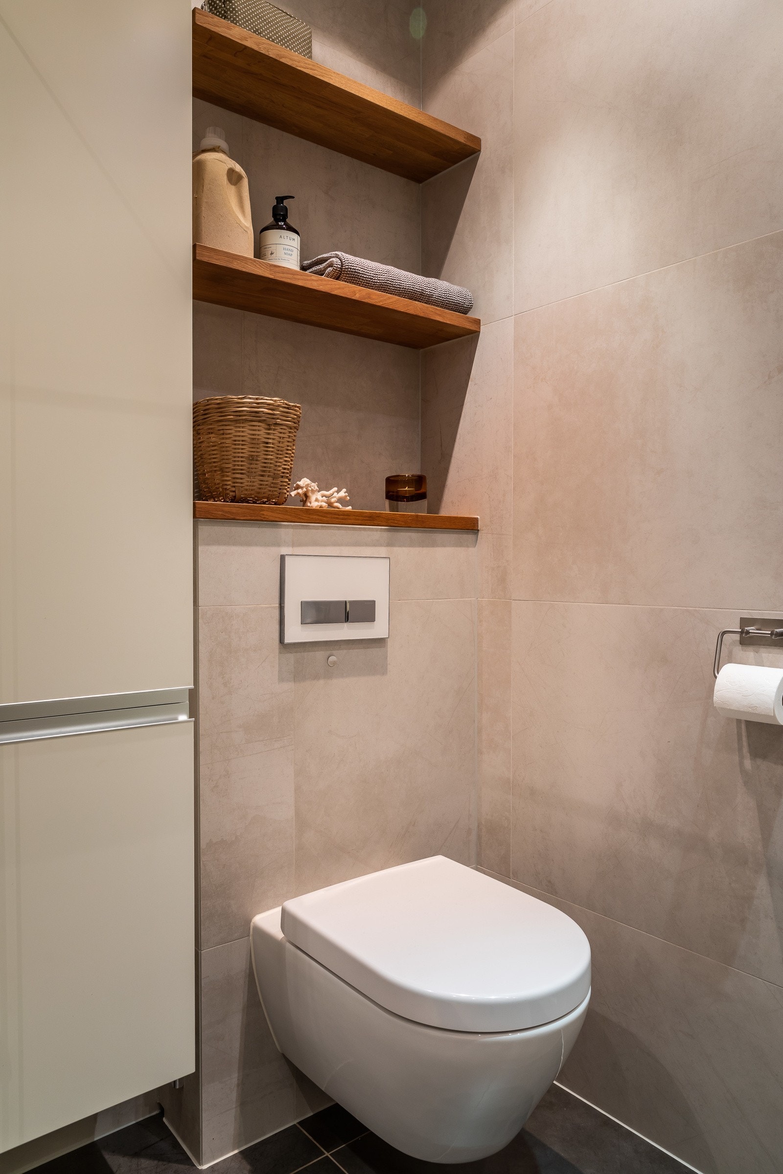 Servant på heltre benkeplate, servantskuffer, regnfallsdusj, hyller i eik og vegghengt toalett. Nisje for vaskemaskin. Galleribilde