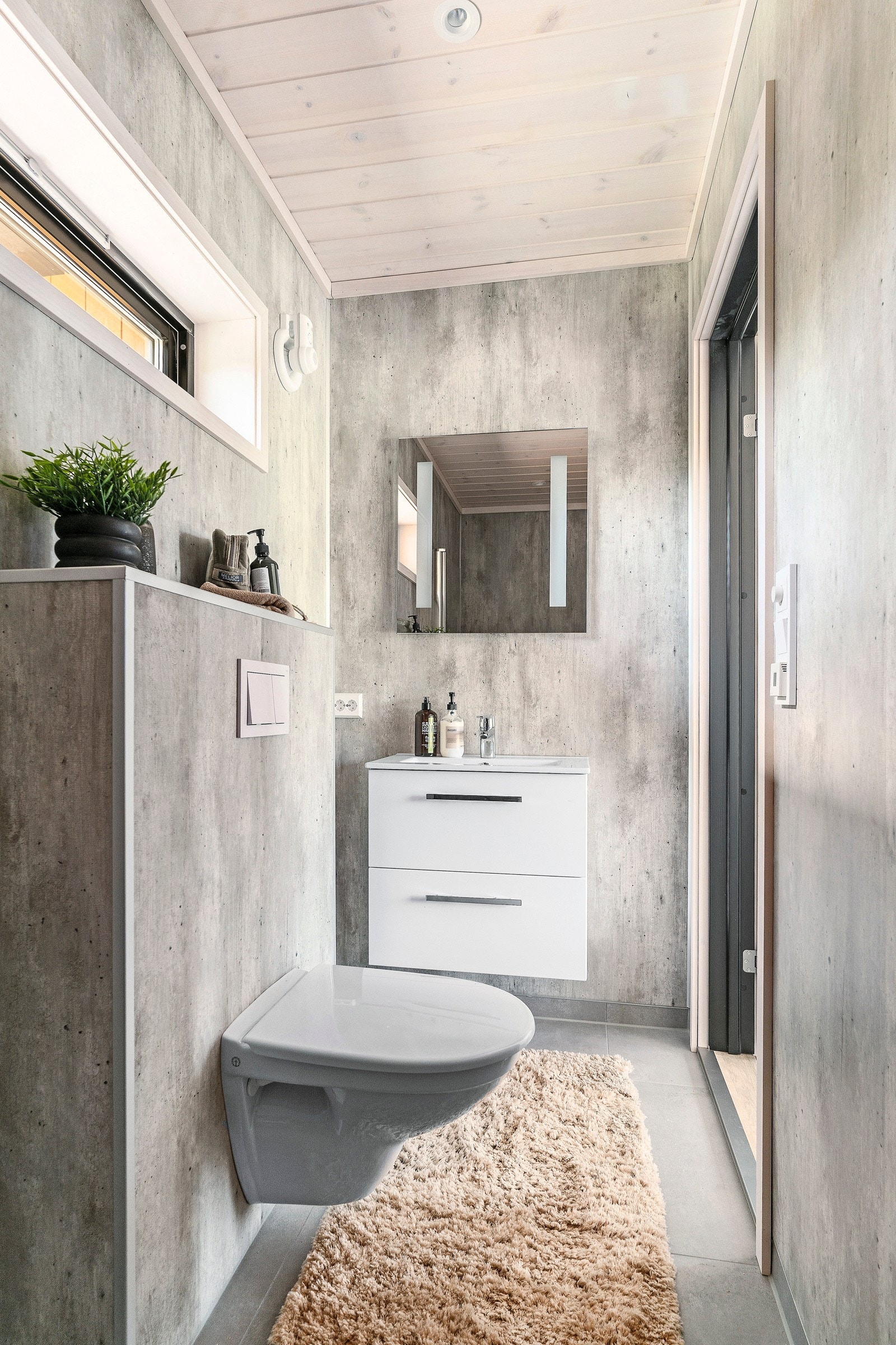 Baderom med direkte adkomst fra hovedsoverom. Utstyrt med vegghengt toalett, dusj og vask i skuffeseksjon med speil Galleribilde