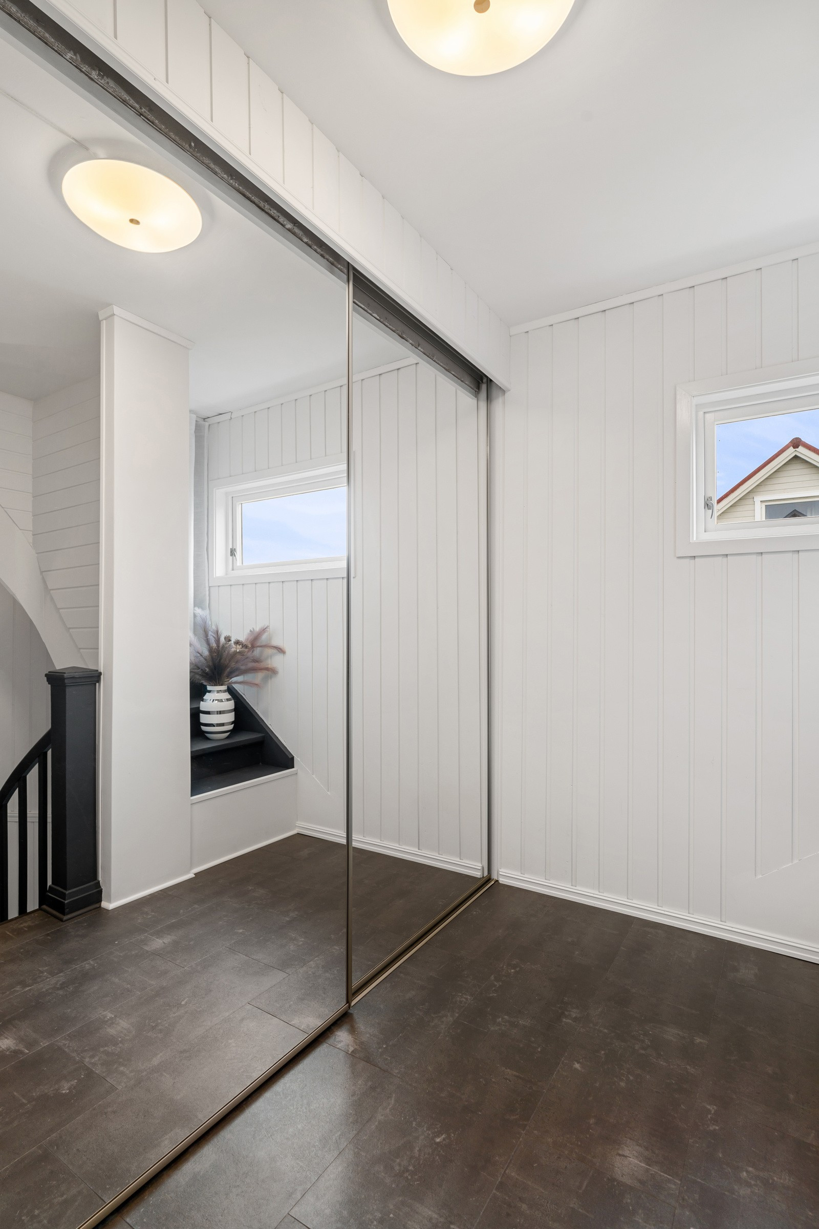 Romslig entrè med lekker skyvedørsgarderobe i speil.