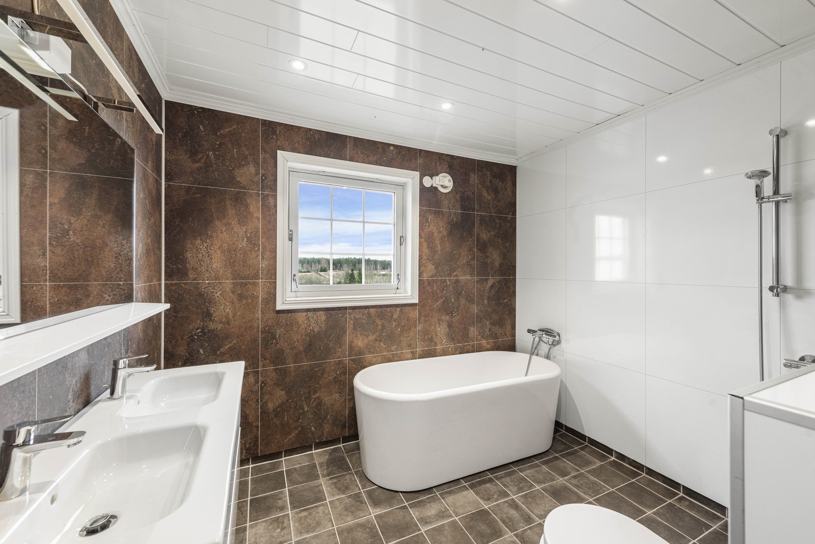 Badet har flislagt gulv med elektrisk gulvvarme og baderomsplater på vegger. Galleribilde