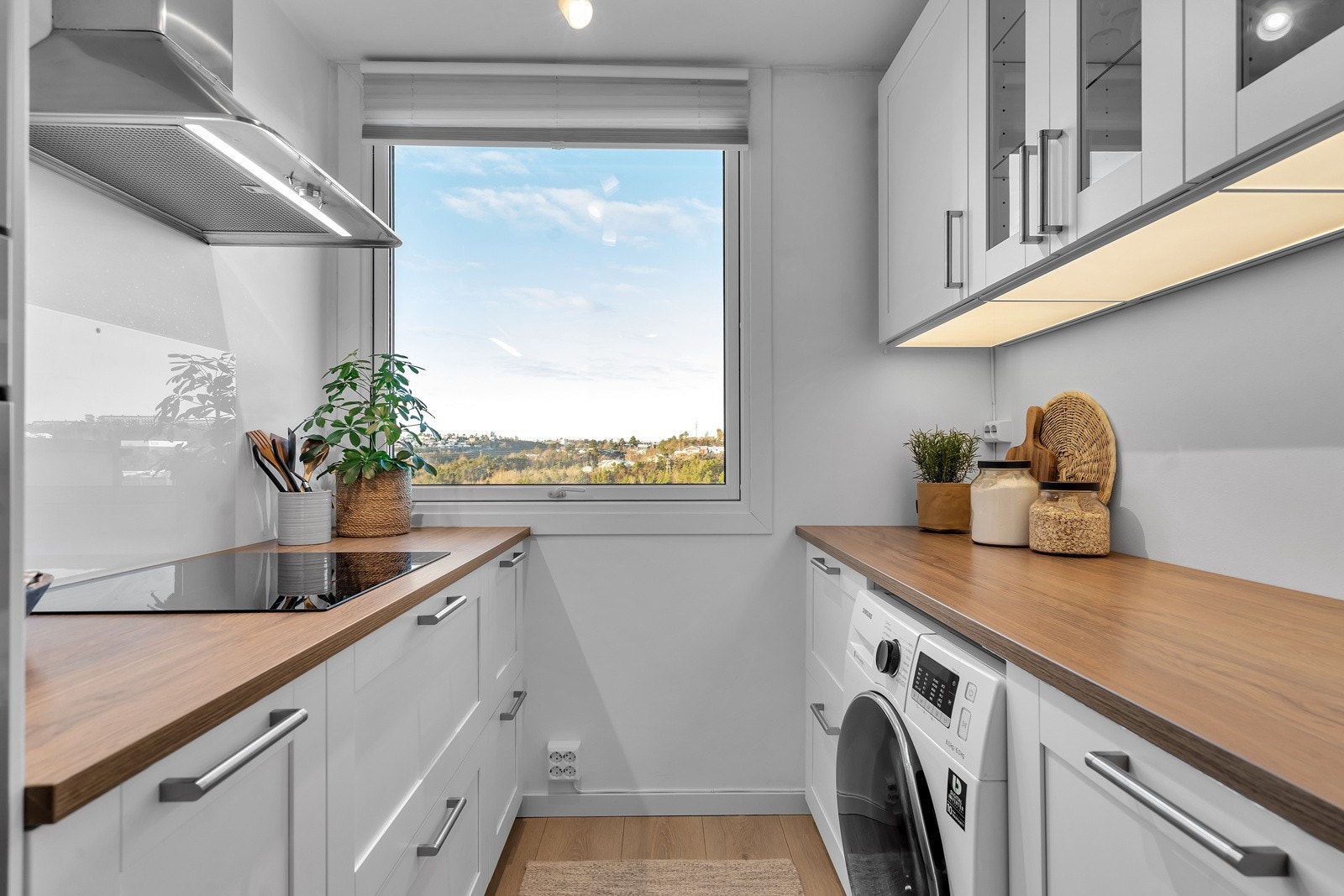 Kjøkkenet inneholder kombiskap, koketopp, ventilator, oppvaskmaskin og vaskemaskin Galleribilde