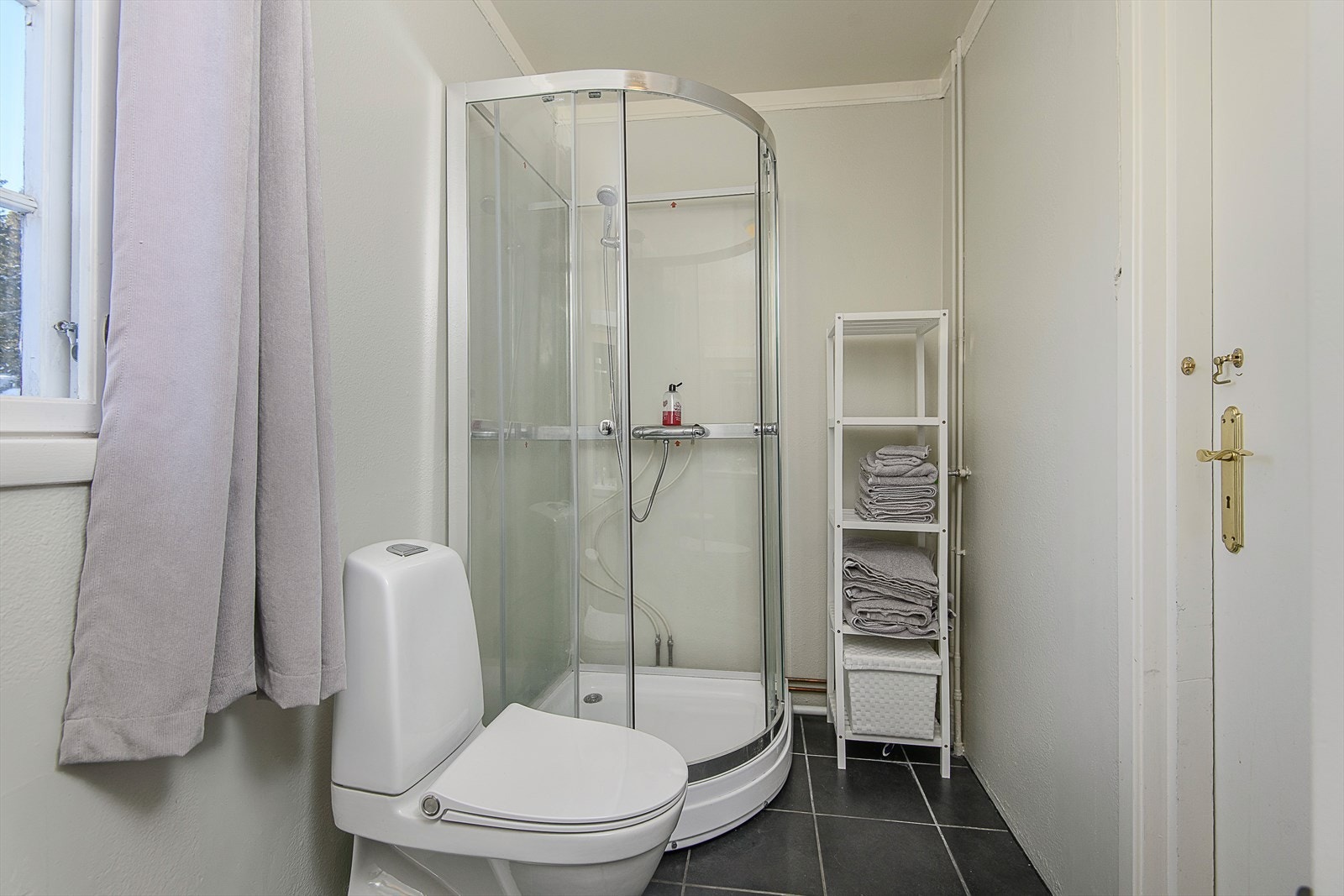 Baderom i 1.etg med servant med underskap, speil med tilhørende belysning, dusjkabinett og gulvmontert WC. Rommet varmes opp via stråleovn. Galleribilde