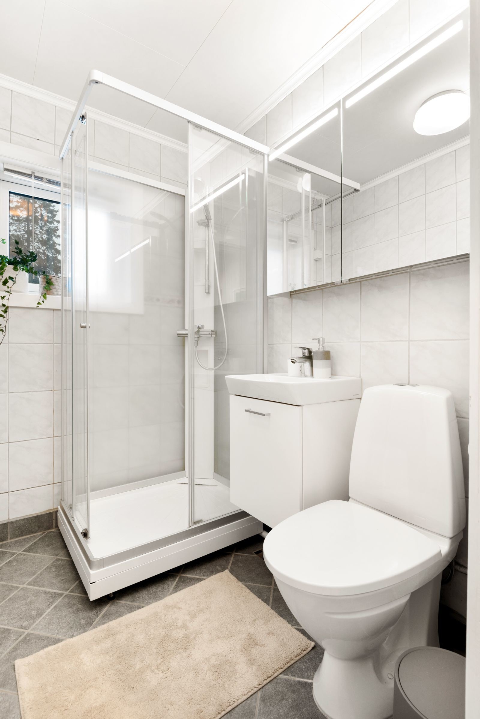 På badet er hver minste kvadratmeter godt utnyttet. Her har du plass til det du trenger i hverdagen! Badet ble enkelt modernisert i 2015 med nye gulvfliser og varmekabler, samt ny baderomsinnredning i 2018. Galleribilde