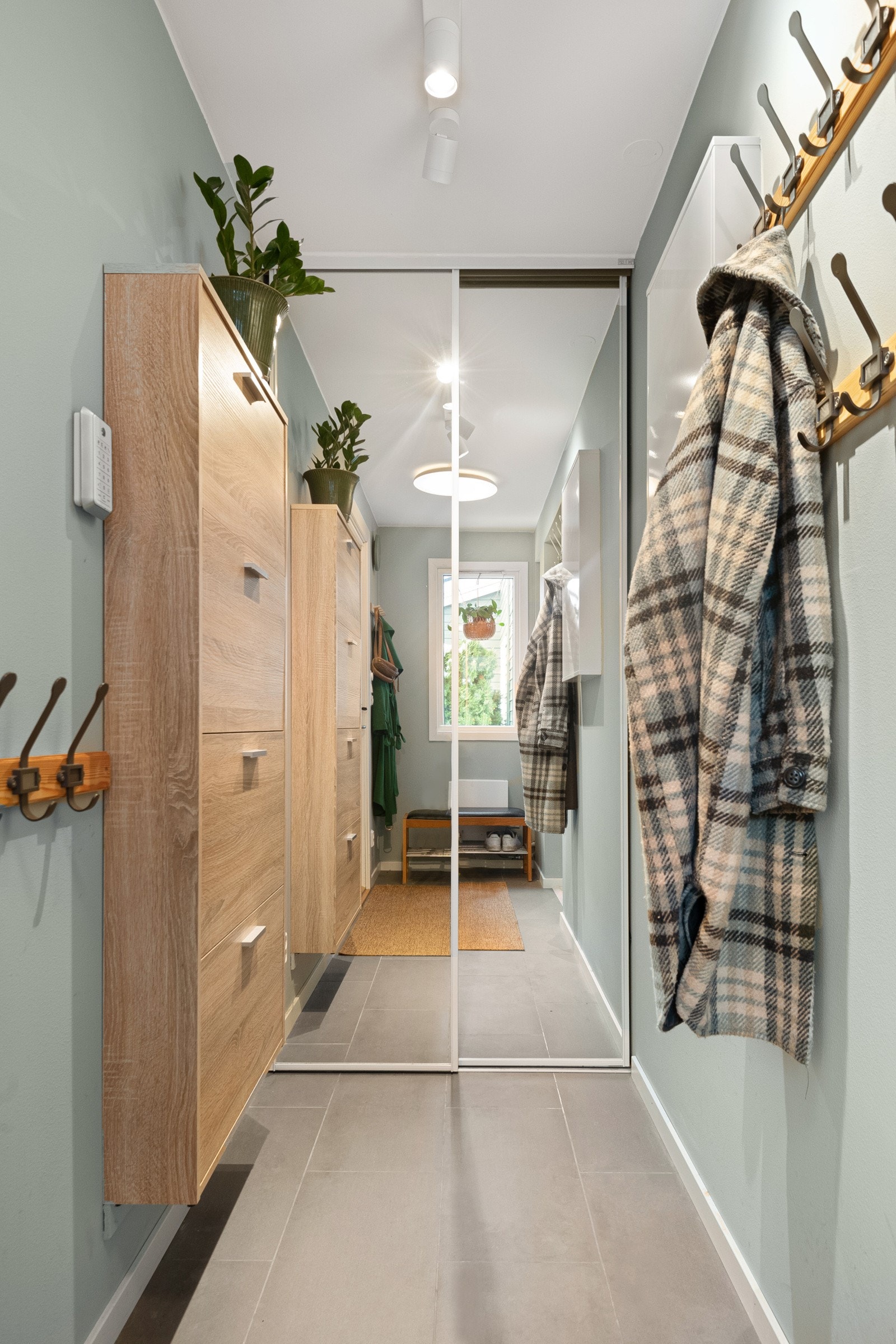 Inngangspartiet er lyst og innbydende, med varmekabler og skyvedørsgarderobe med speil Galleribilde