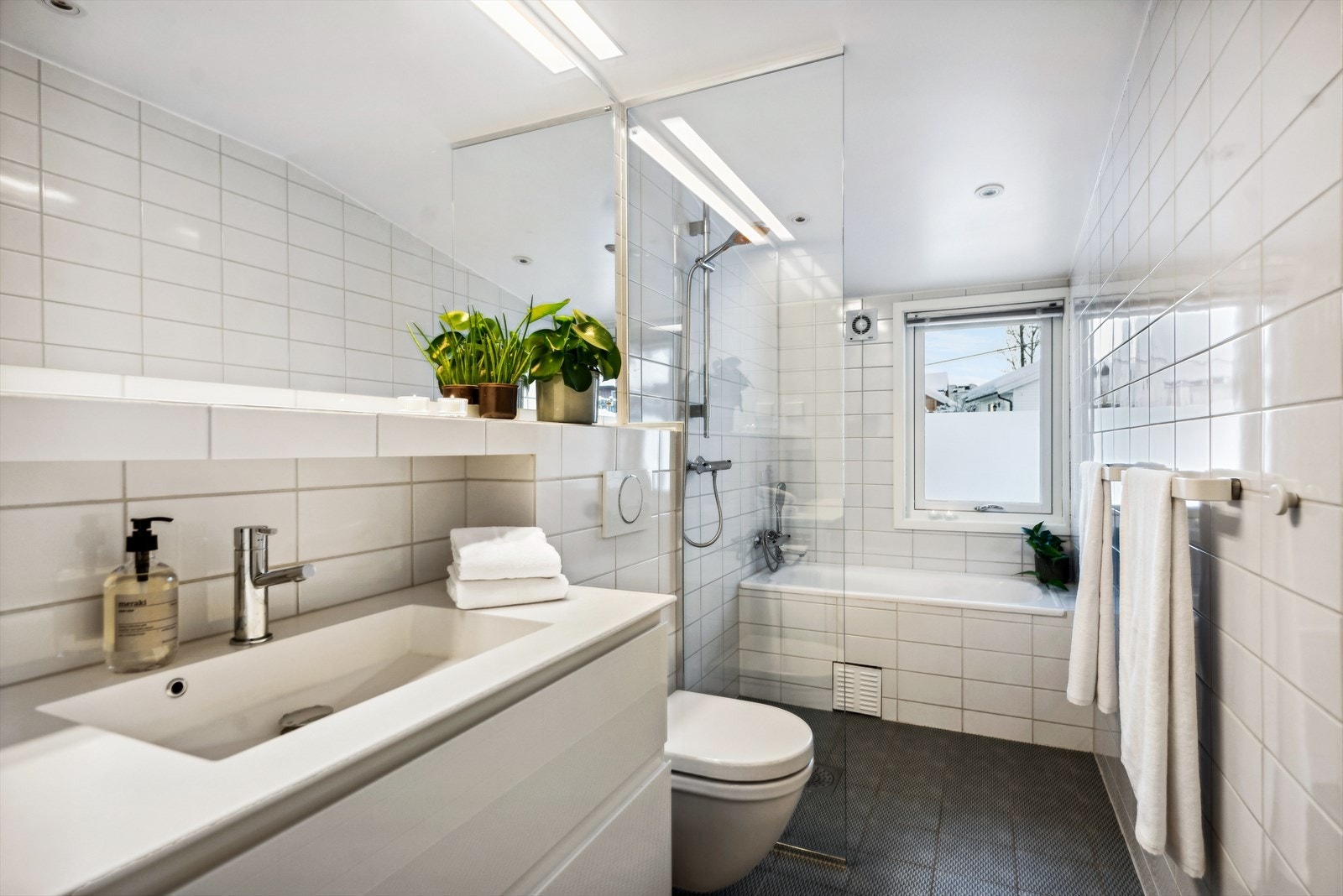 Flislagt bad fra 2014 med varmekabler, badekar, dusjplass og vegghengt toalett. Galleribilde