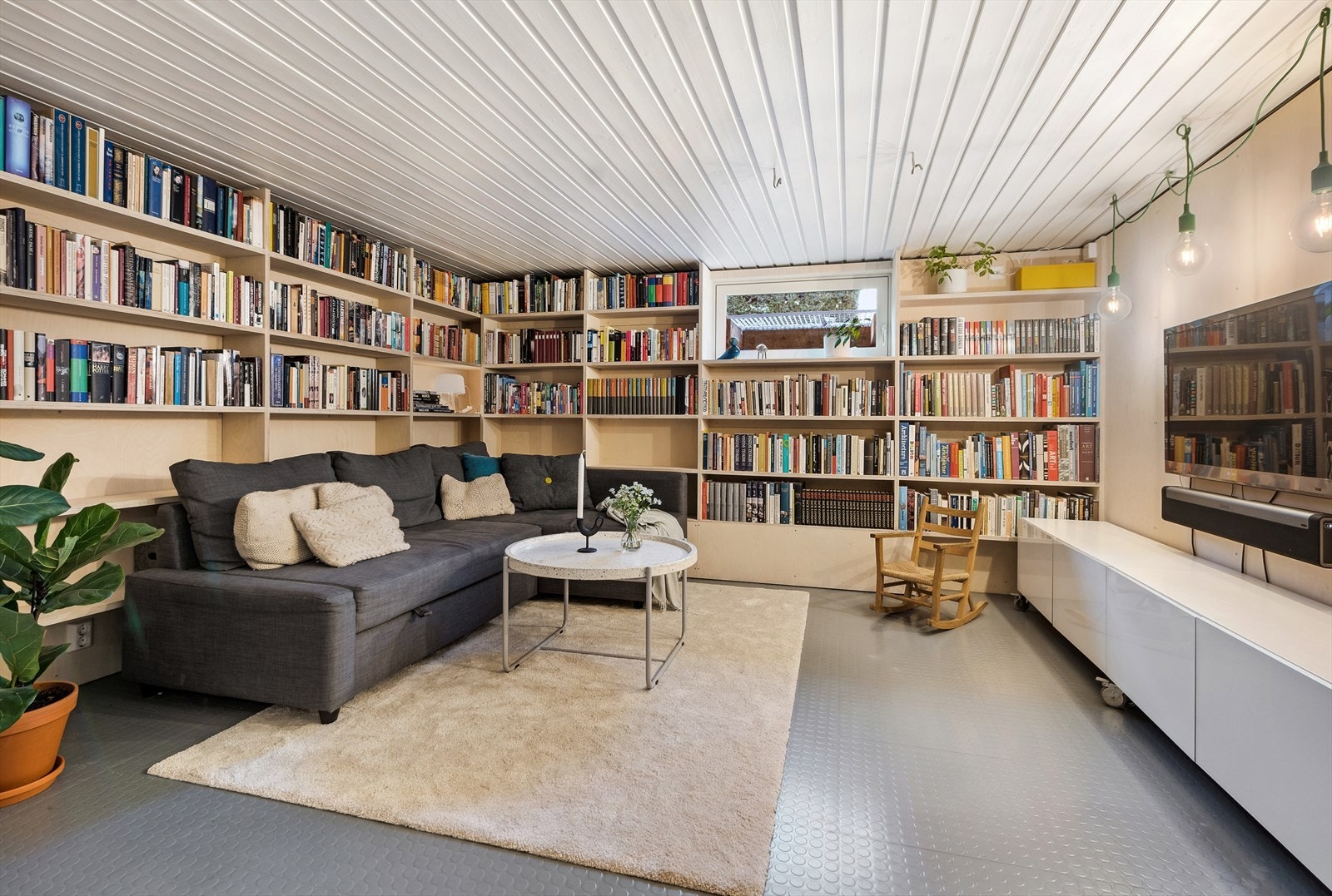 Praktisk innredning med plassbygde bokhyller og vegger i bjørkefinér. Galleribilde