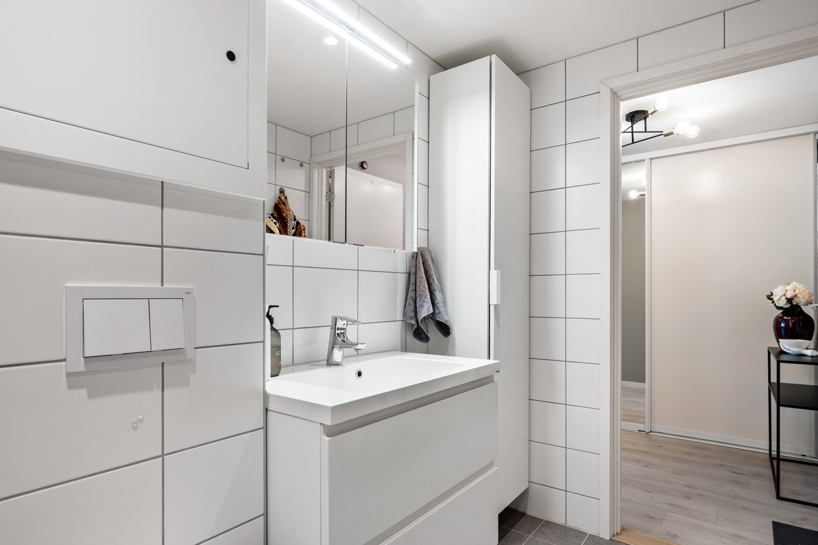 Badet består av dusjhjørne med dører i herdet glass, speilskap med overliggende høyskap, høyskap med glatt front og heldekkende servant, samt veggmontert toalett. Galleribilde